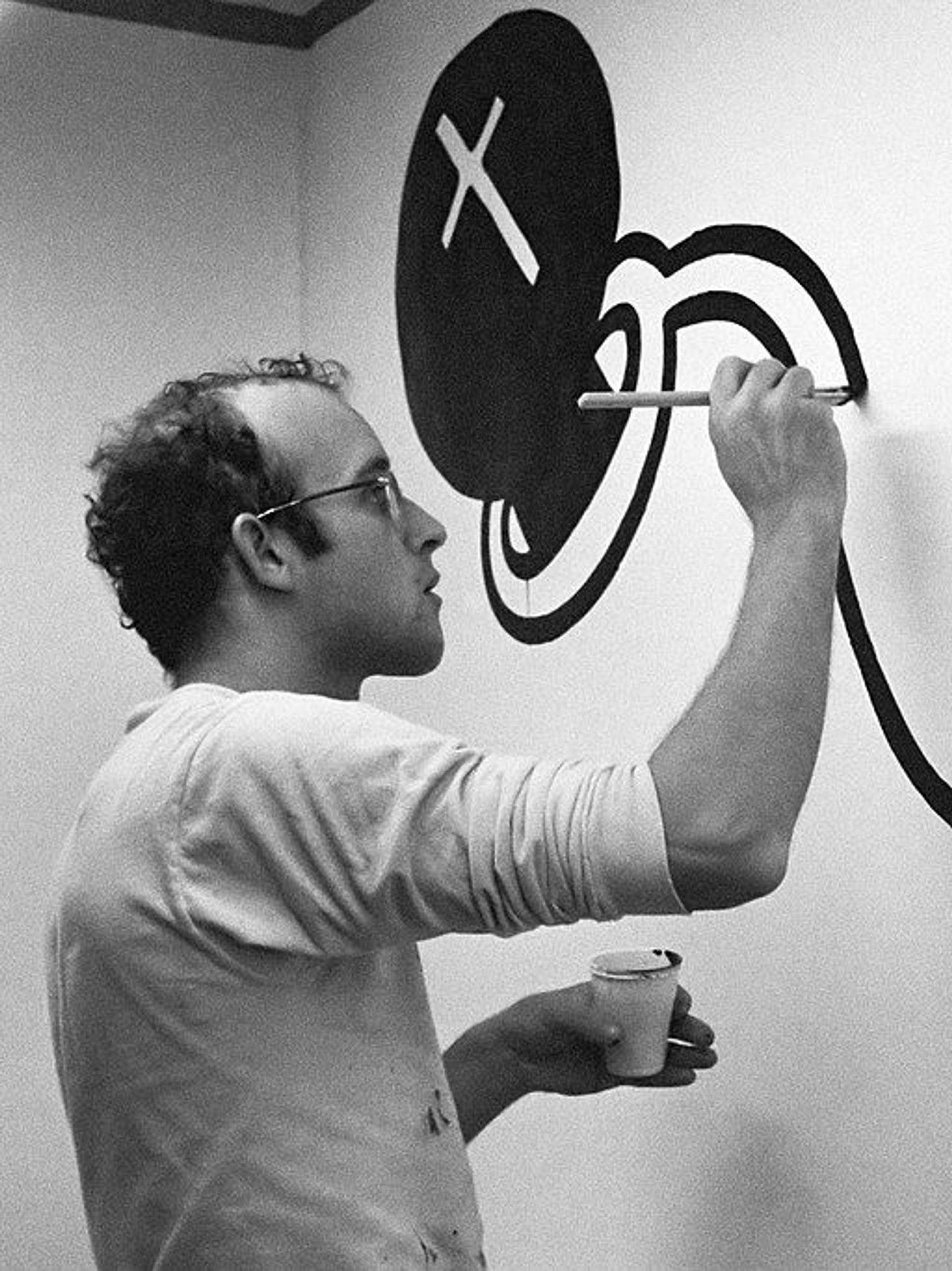 Keith Haring painting line art onto a wall.