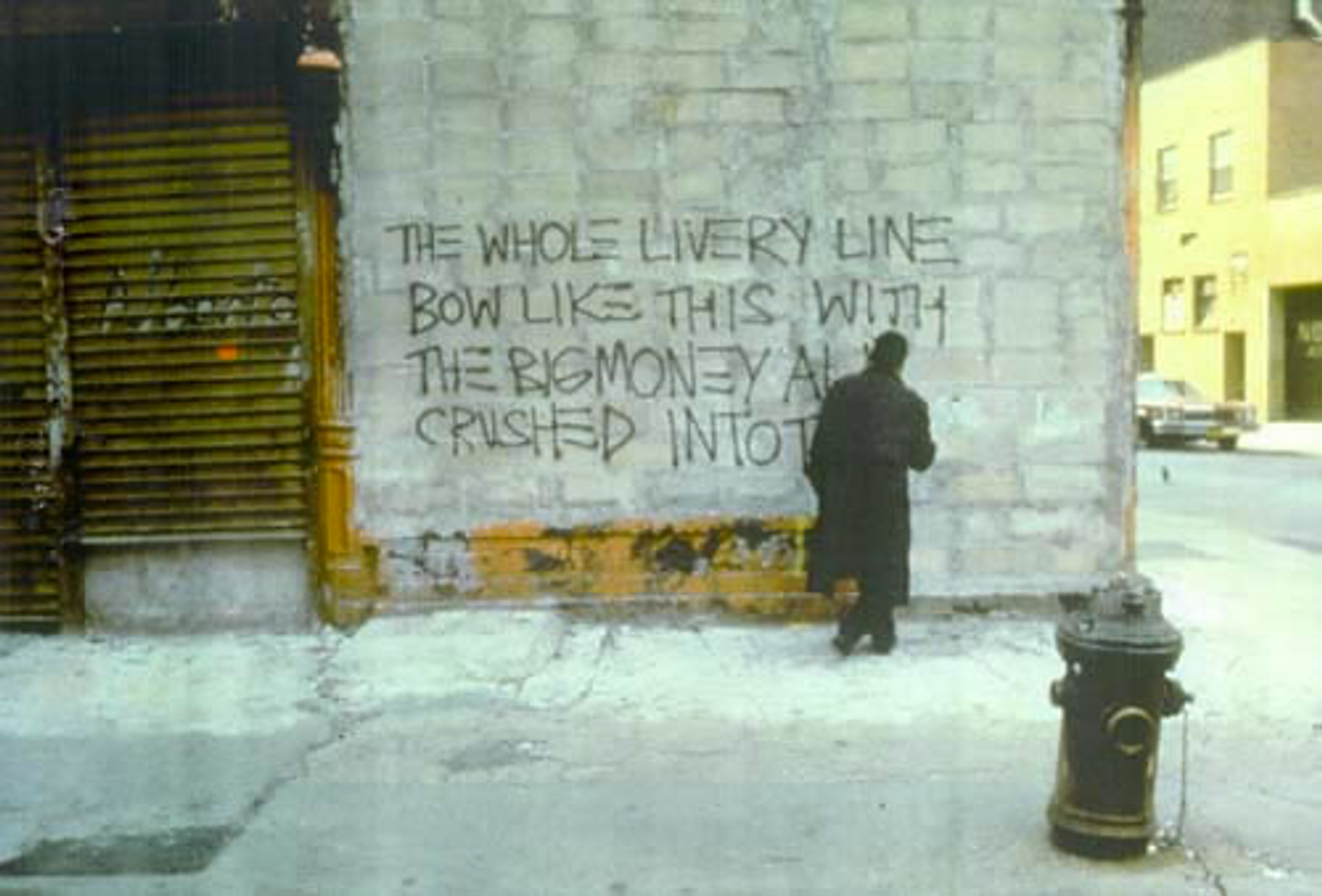 This photograph shows Basquiat spraypainting on a wall the lines: the whole livery line  bow like this with  the big money all  crushed into these feet
