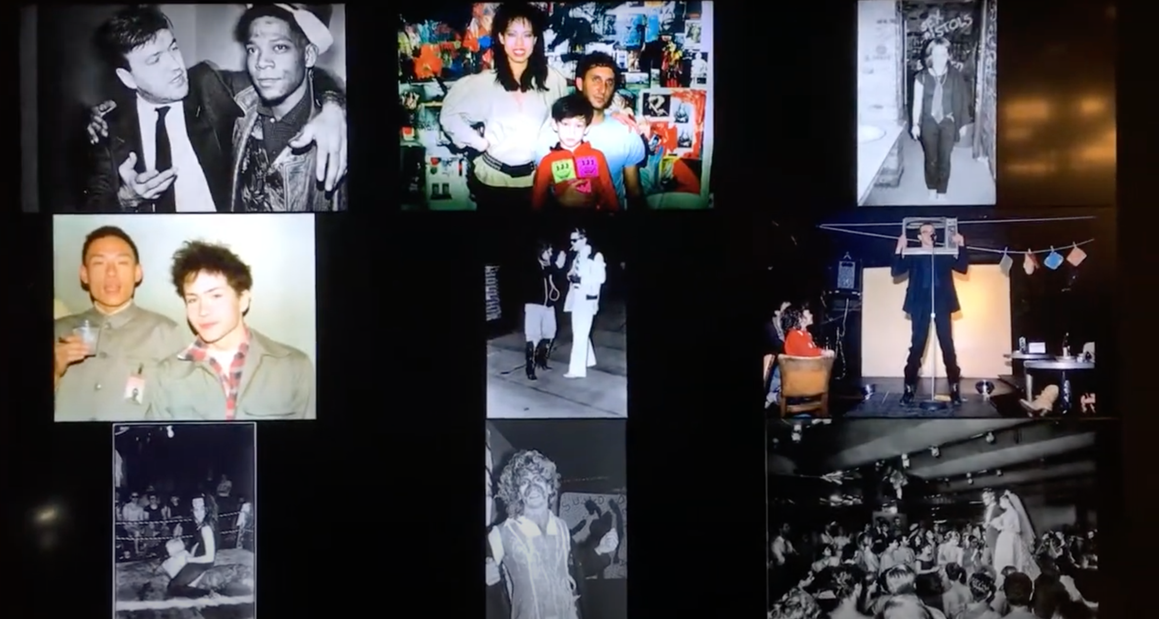 Installation View of MoMA's Club 57 retrospective. Artist Jean-Michel Basquiat can be seen in the top left corner, while Keith Haring is seen performing in the centre right.