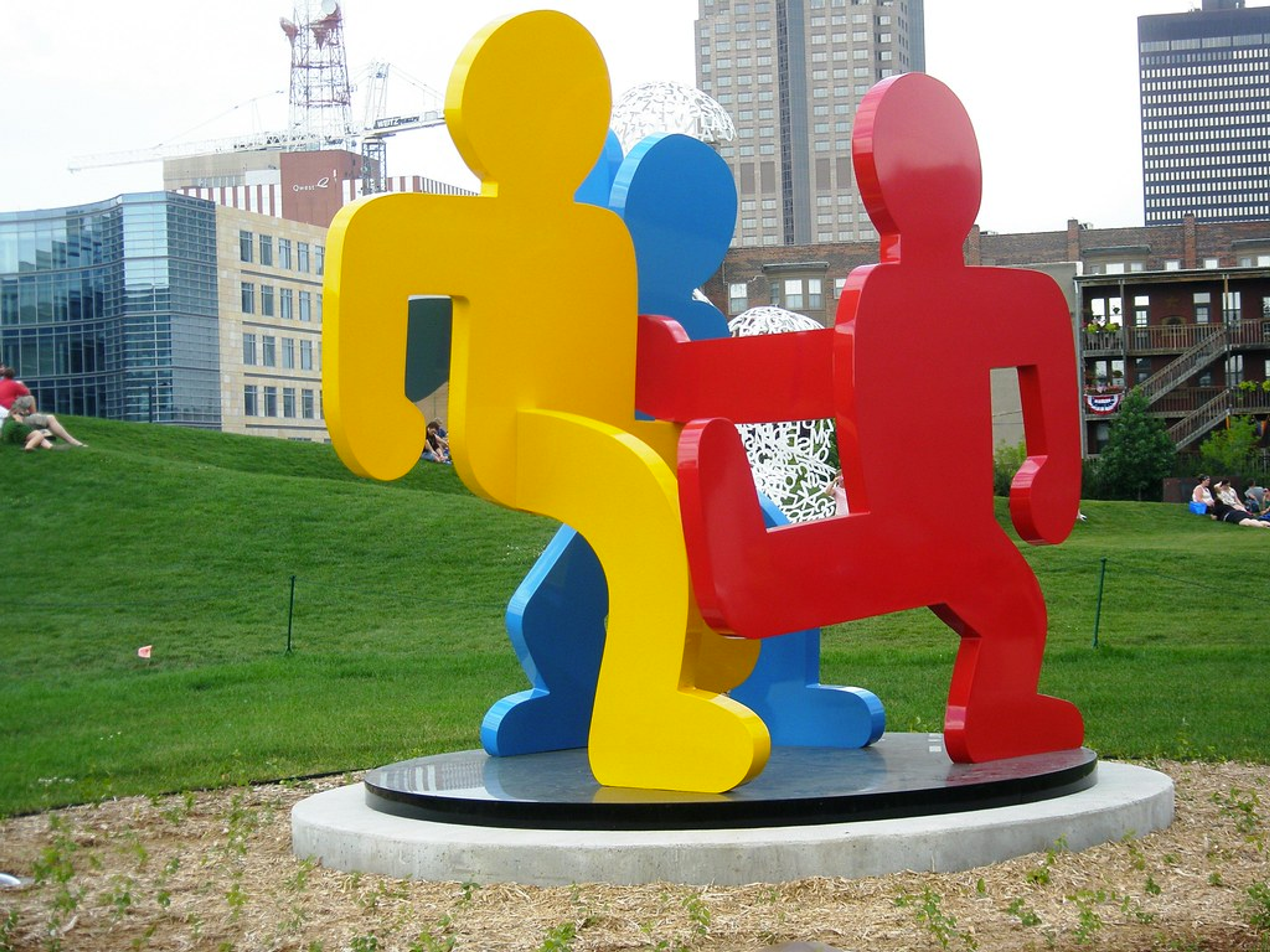 Keith Haring’s Untitled (Dancing Figures) Version C.  An installation view of a red and blue painted steel sculpture on an elevated grey platform. 