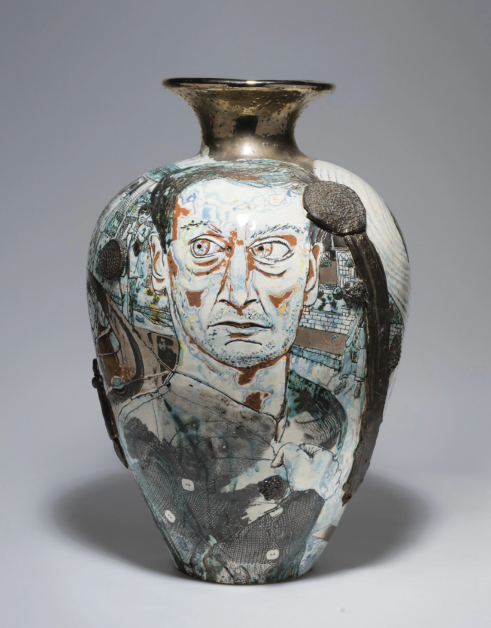 A detailed ceramic vase by Grayson Perry adorned with a rich array of characters (including Lucian Freud), text, and patterns, displaying Perry's distinctive use of traditional pottery to convey contemporary social commentary.