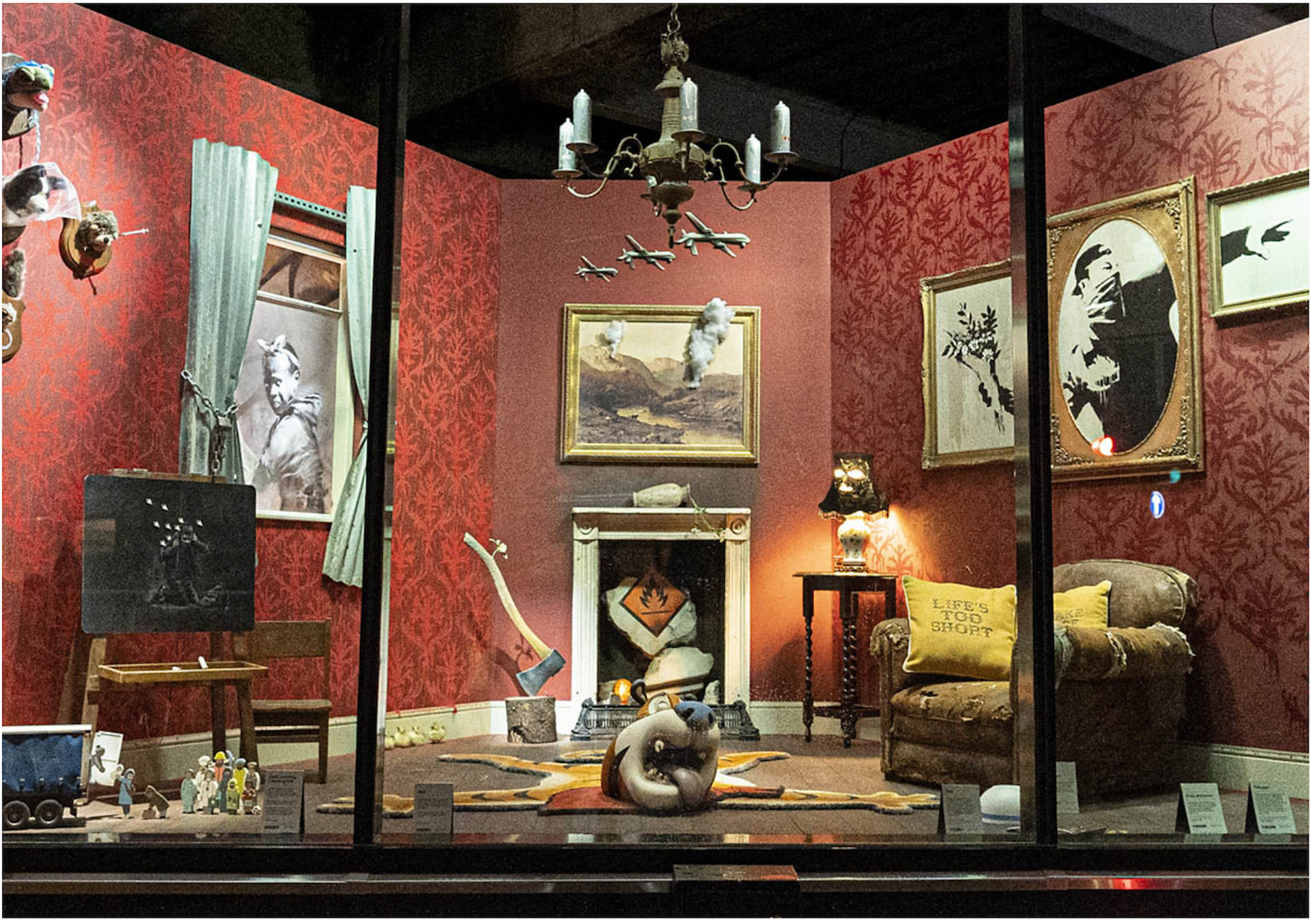 A photo showing the interior of Banksy's pop-up storefront, Gross Domestic Product, as seen through illuminated windows.