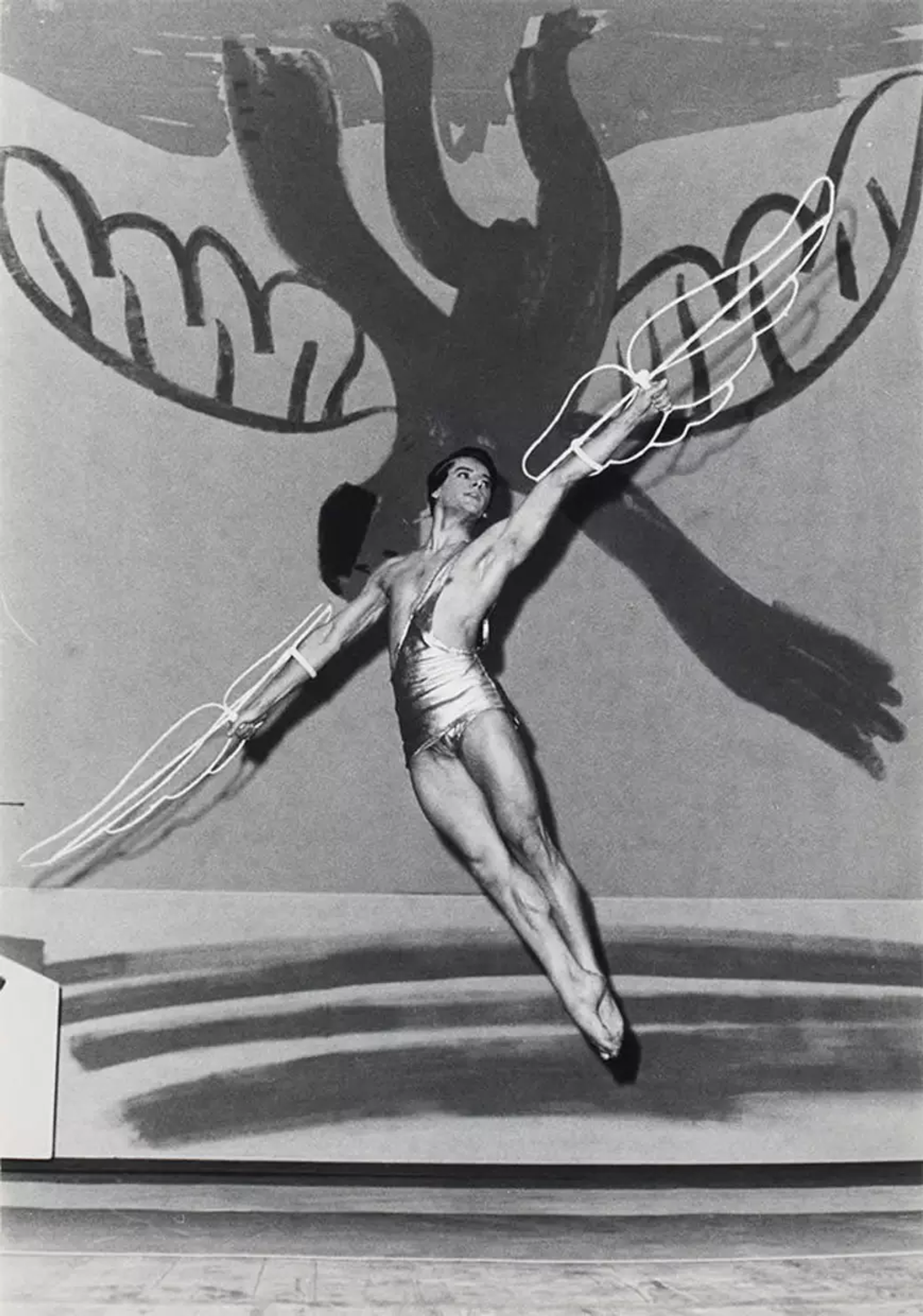 A monochrome image of a dancer, wearing wire wings, against a backdrop of icarus’ fall painted by Pablo Picasso.