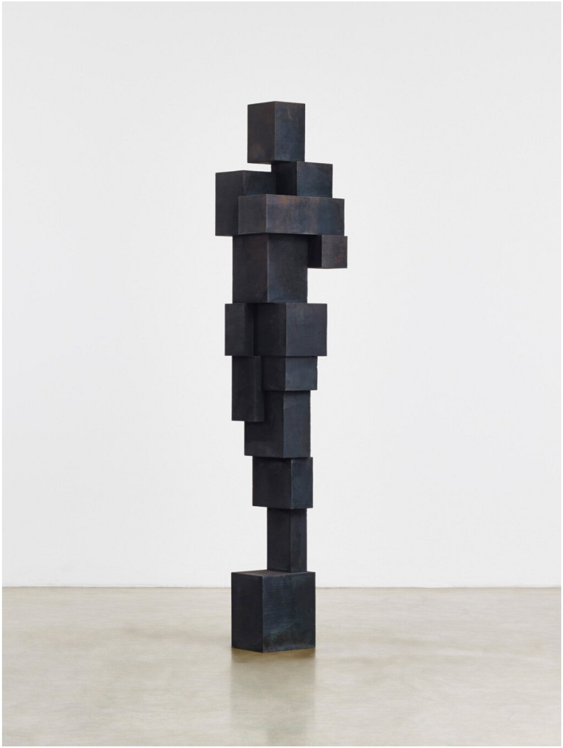  A life-sized sculpture of the human figure, devoid of any defining characteristics, capturing the essence of the human form. The sculpture is constructed using stacked iron blocks and is photographed in a white, empty gallery space.