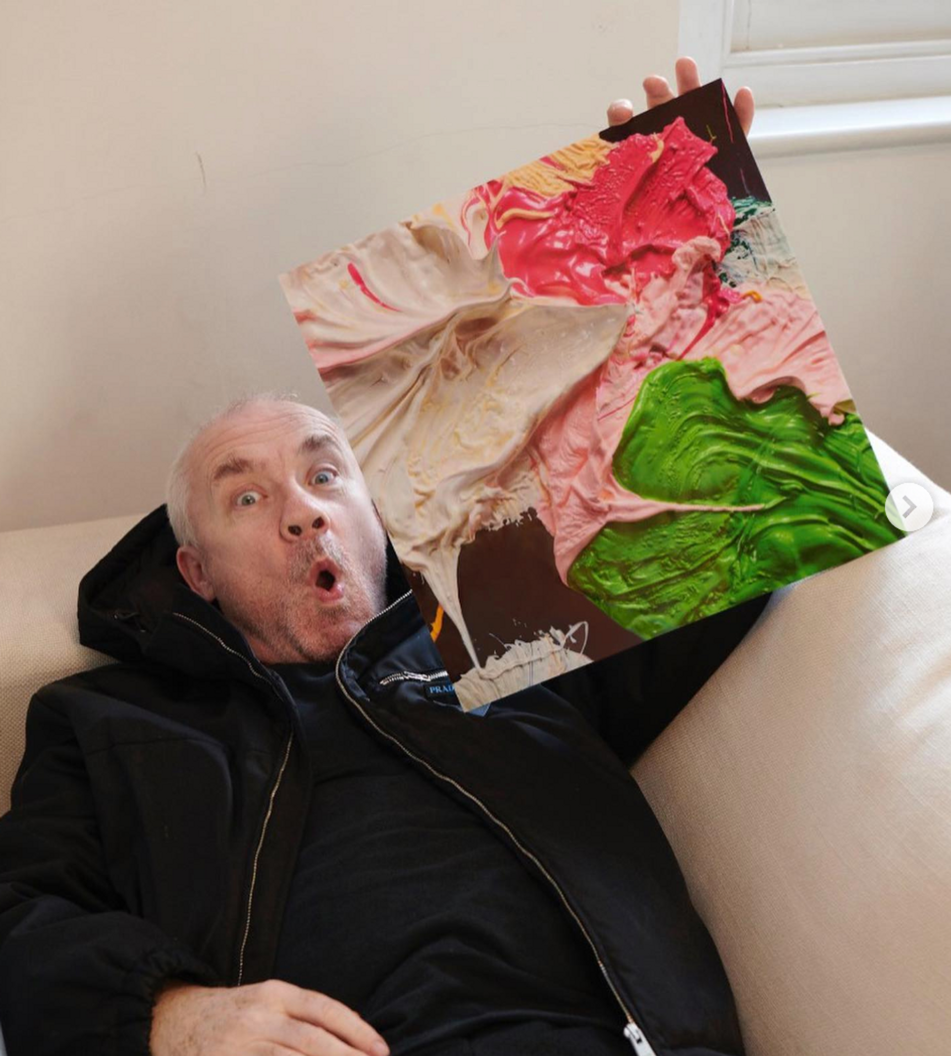 An image of the artist Damien Hirst holding up one of his works from the Fruitful And Forever series.