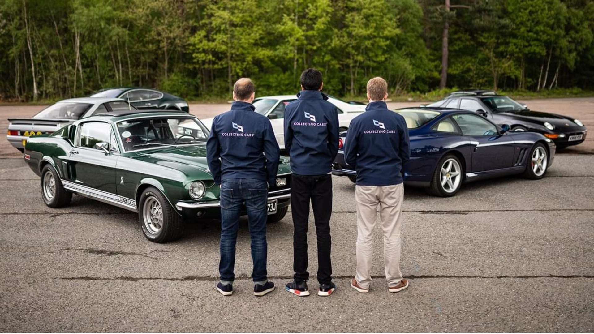 An image of three people, wearing “Collecting Cars” jackets, standing in front of a group of classic cars.