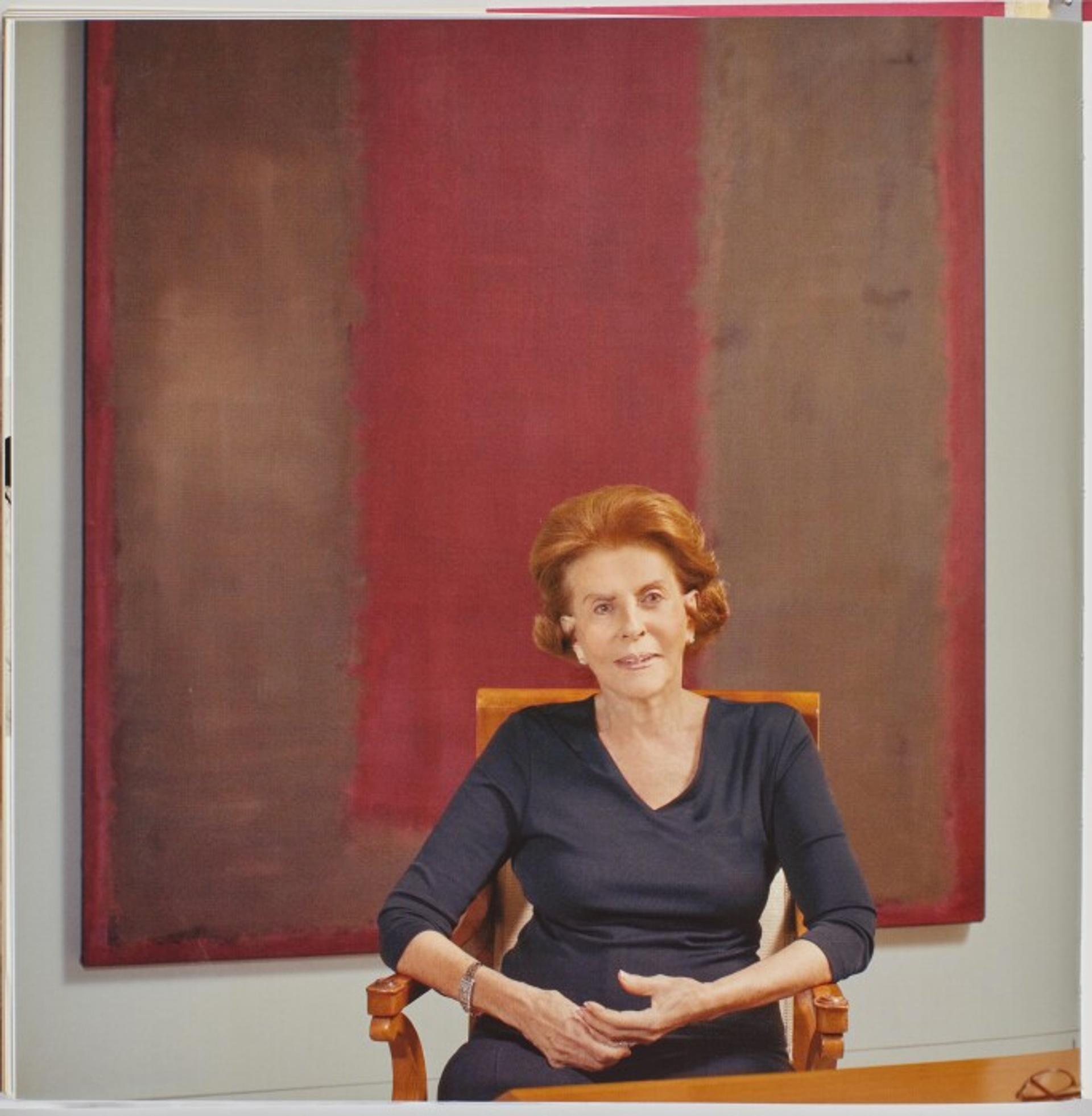 A photograph of Emily Fisher Landau posing in front of a 1958 Untitled work by Mark Rothko. She is shown wearing a navy blue dress.