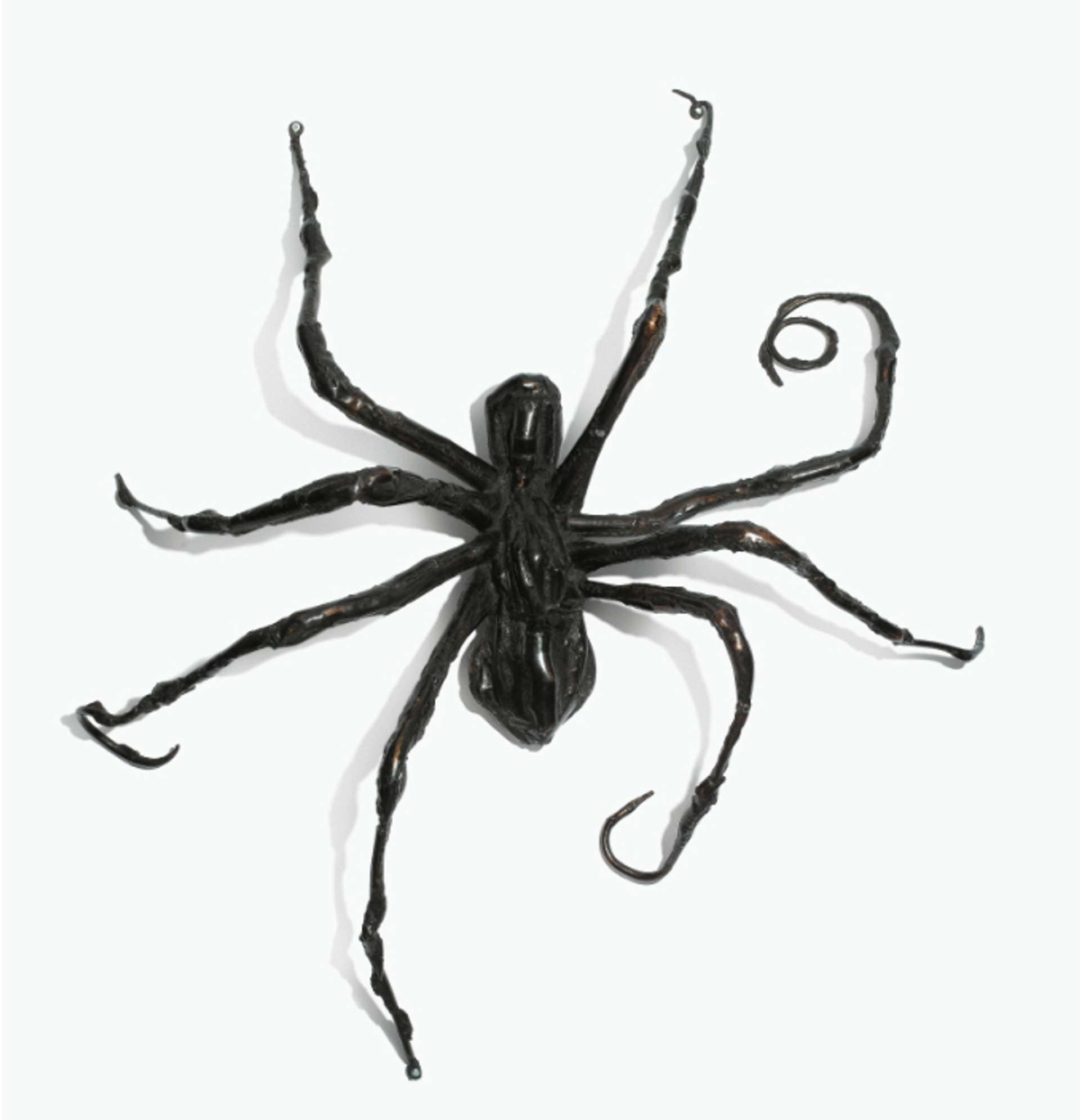 A wall relief spider sculpture climbing upwards, its eight limbs spread out, with two on the left slightly curled inward, conveying a sense of movement.