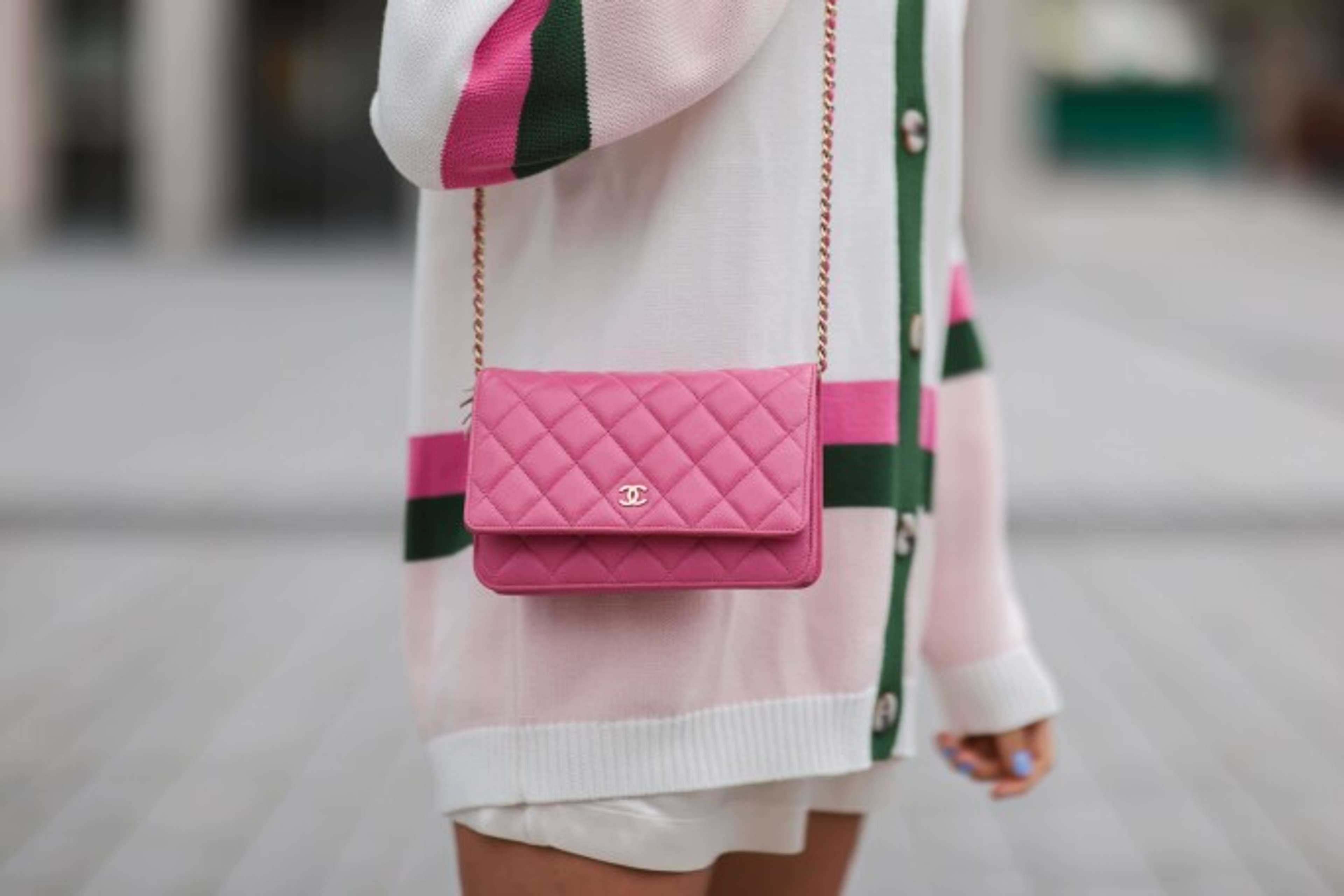 An image of a model wearing a bright pink Chanel Wallet On Chain.