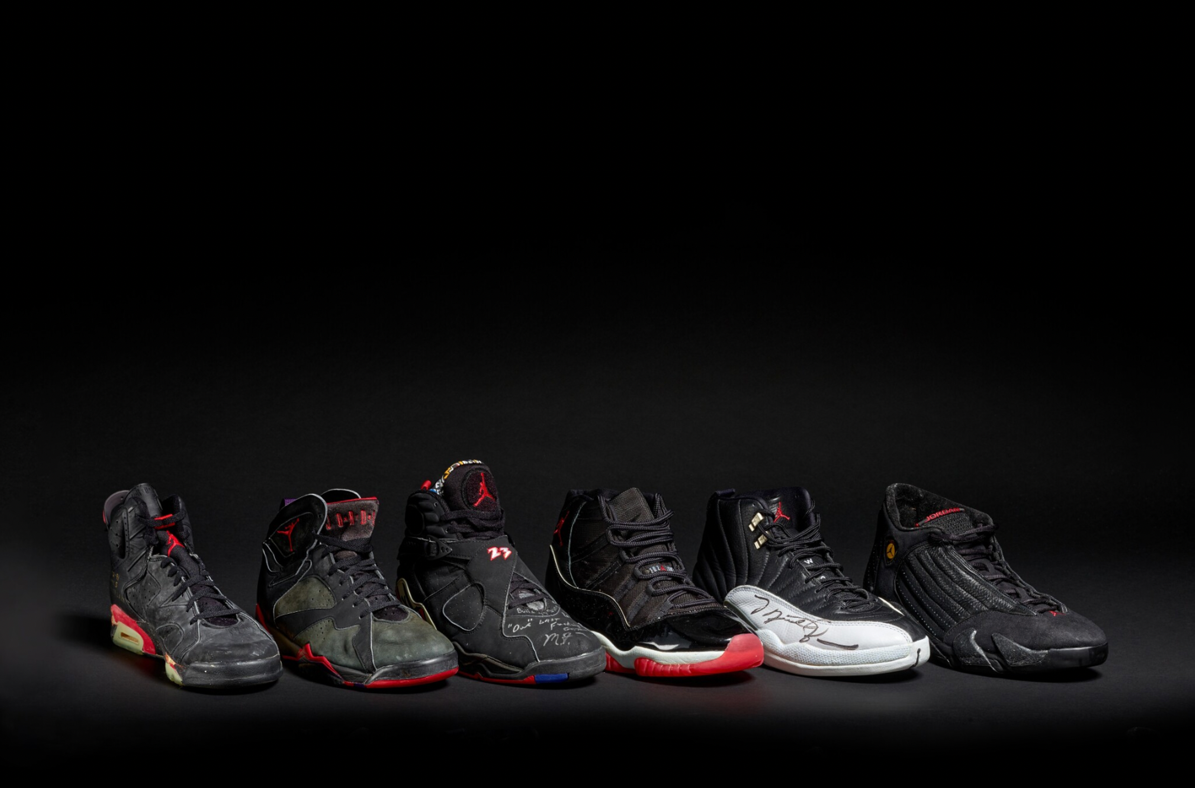 A photograph of six Michael B Jordan sneakers lined up, set against a black studio background with dramatic lighting on the shoes