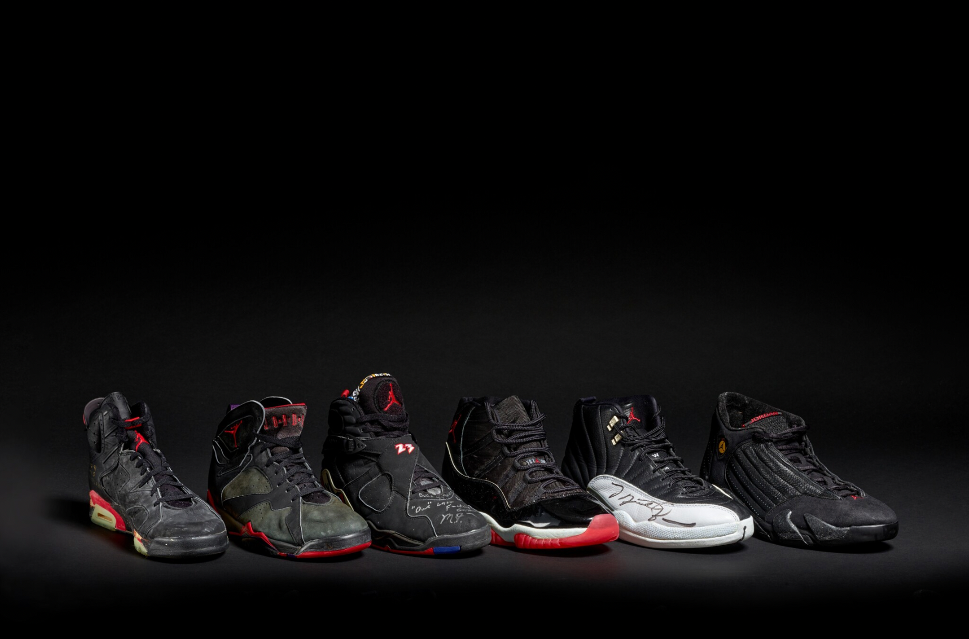 A photograph of six Michael B Jordan sneakers lined up, set against a black studio background with dramatic lighting on the shoes