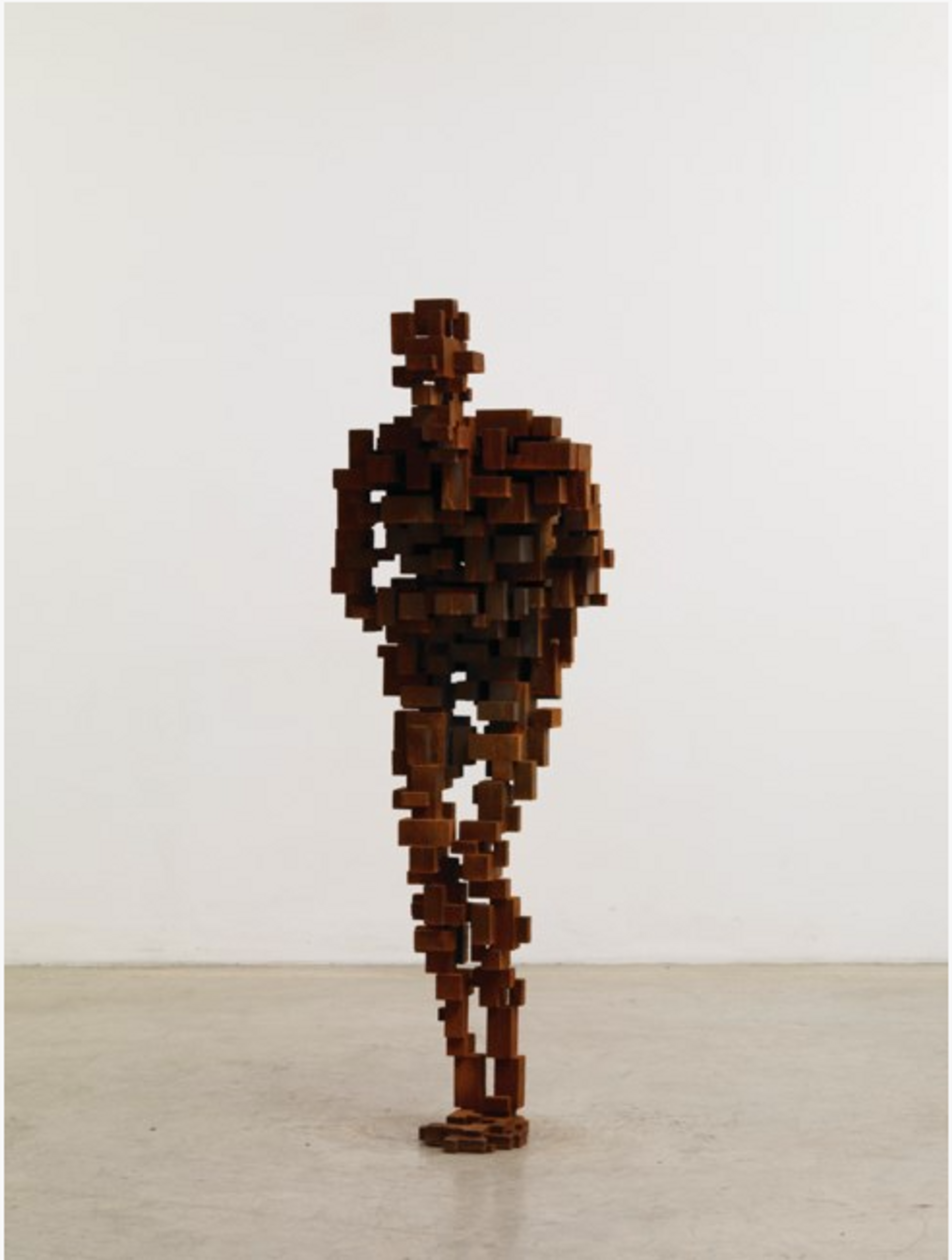 A life-sized sculpture of the human form, depicted in a crouched position with bent knees and both arms wrapped around its torso. The sculpture is constructed using tessellating and stacked iron cubes.