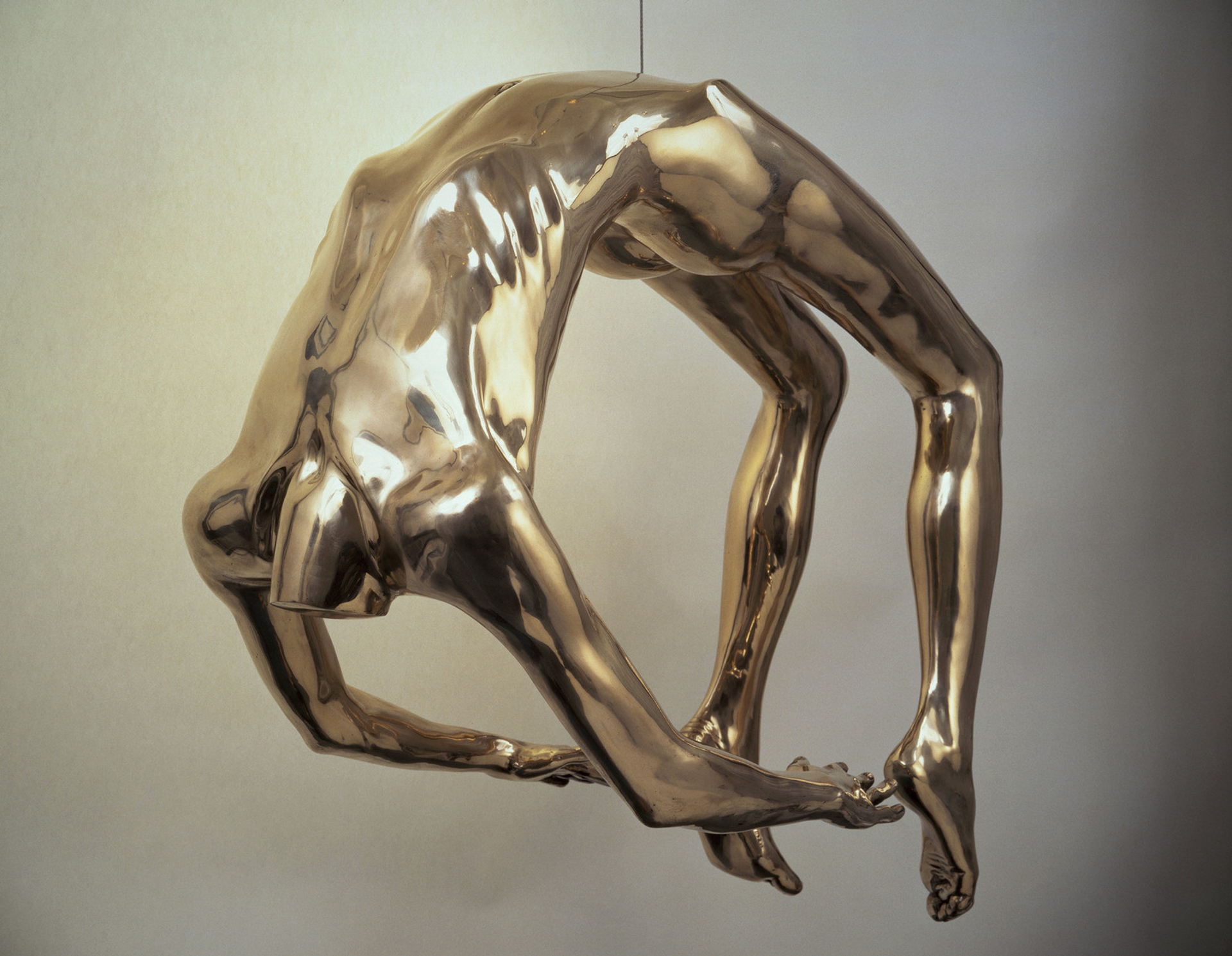 Photograph of artist Louise Bourgeois’ Arch Of Hysteria bronze statue. A headless figure that has an arch in their back from bending over backwards, touching the heels of their feet.  