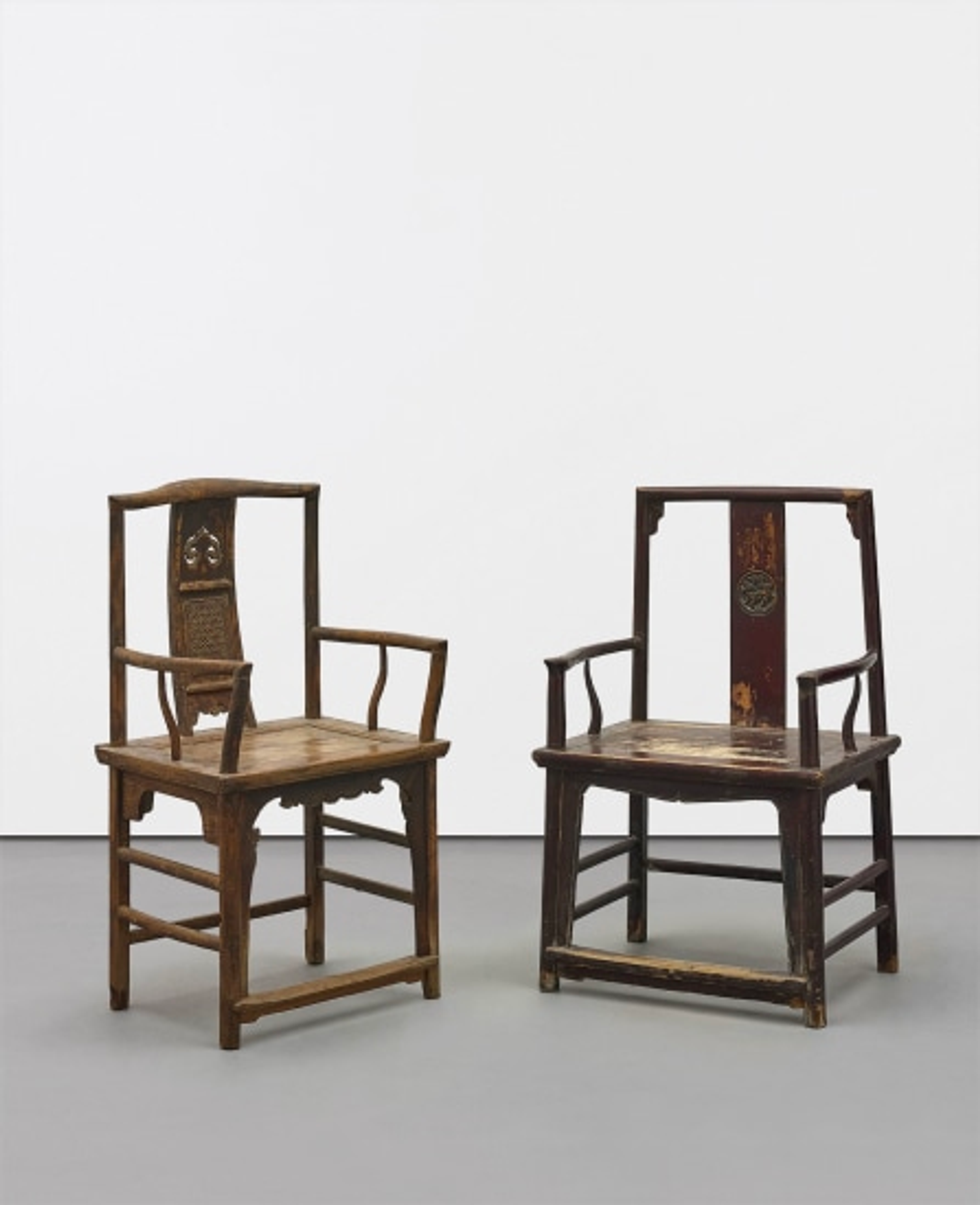 Two empty wooden chairs with ornate details displayed in gallery