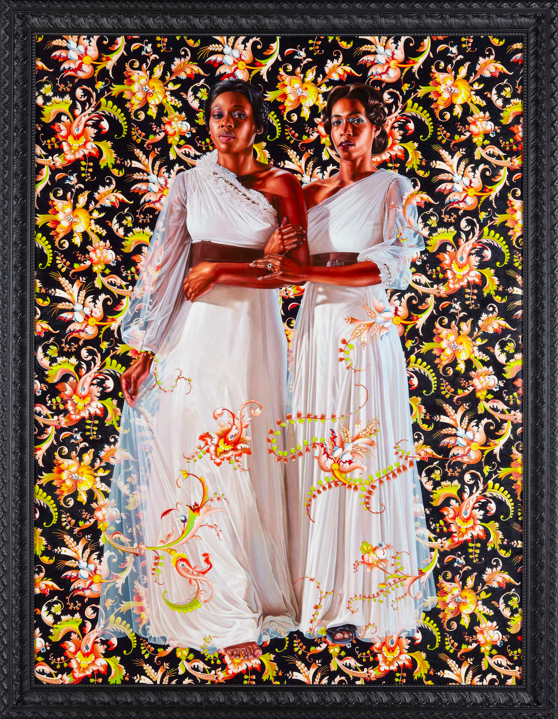 Two tall black women in white ball gowns, crossing over their shoulders, stand side by side. One woman extends her dress outward while both link arms and make eye contact with the viewer. They are positioned against a black background with ornate pink, yellow, and green floral foliage.