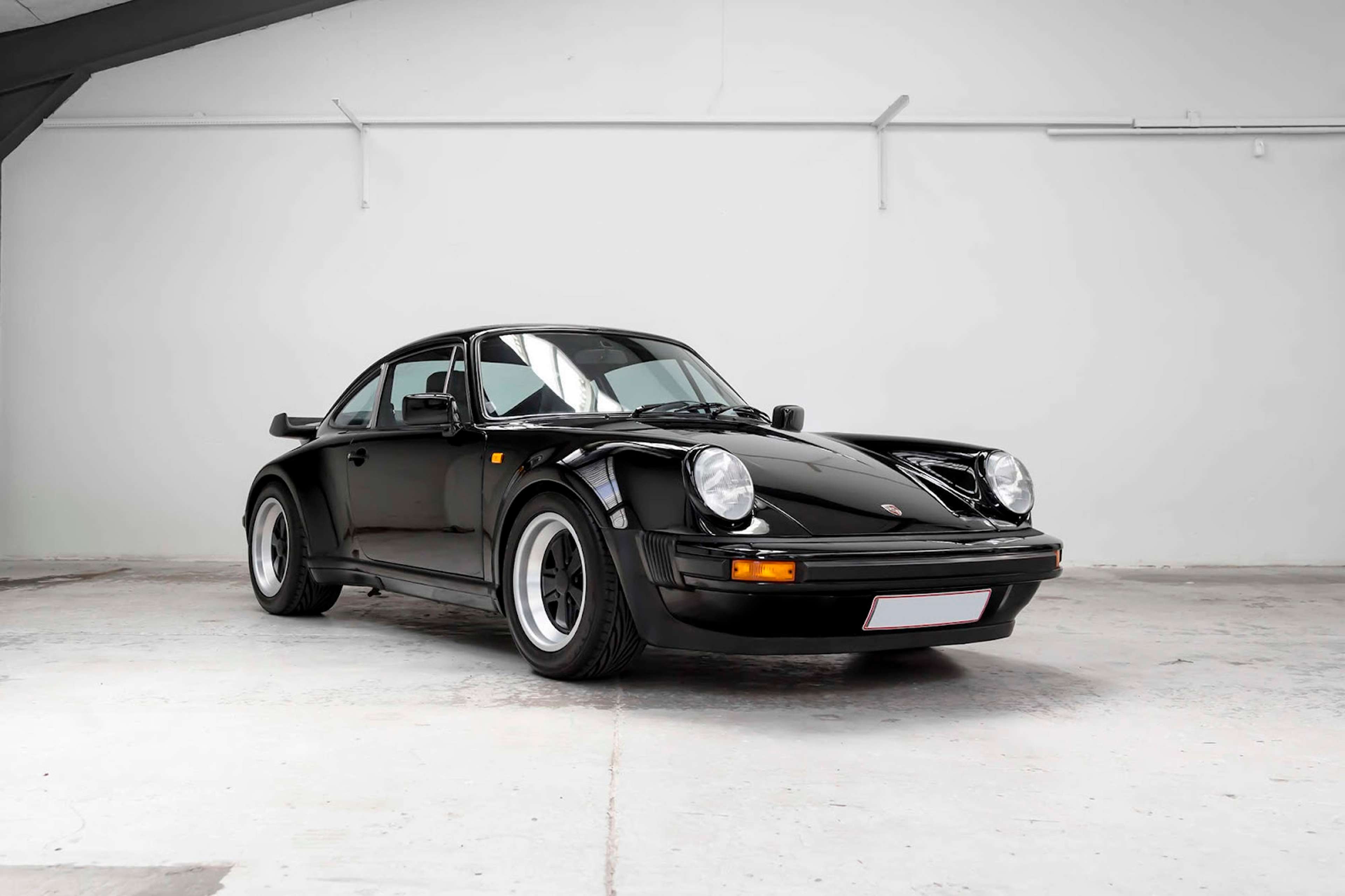 A black Porsche 930 Turbo in a garage.