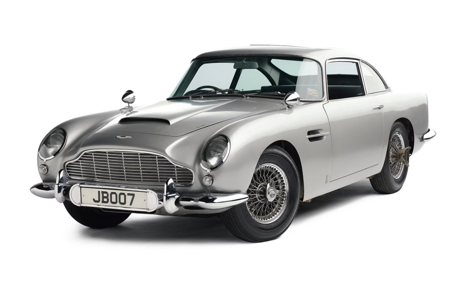 A silver 1965 Aston Martin DB5 against a white background, featured in the James Bond film.