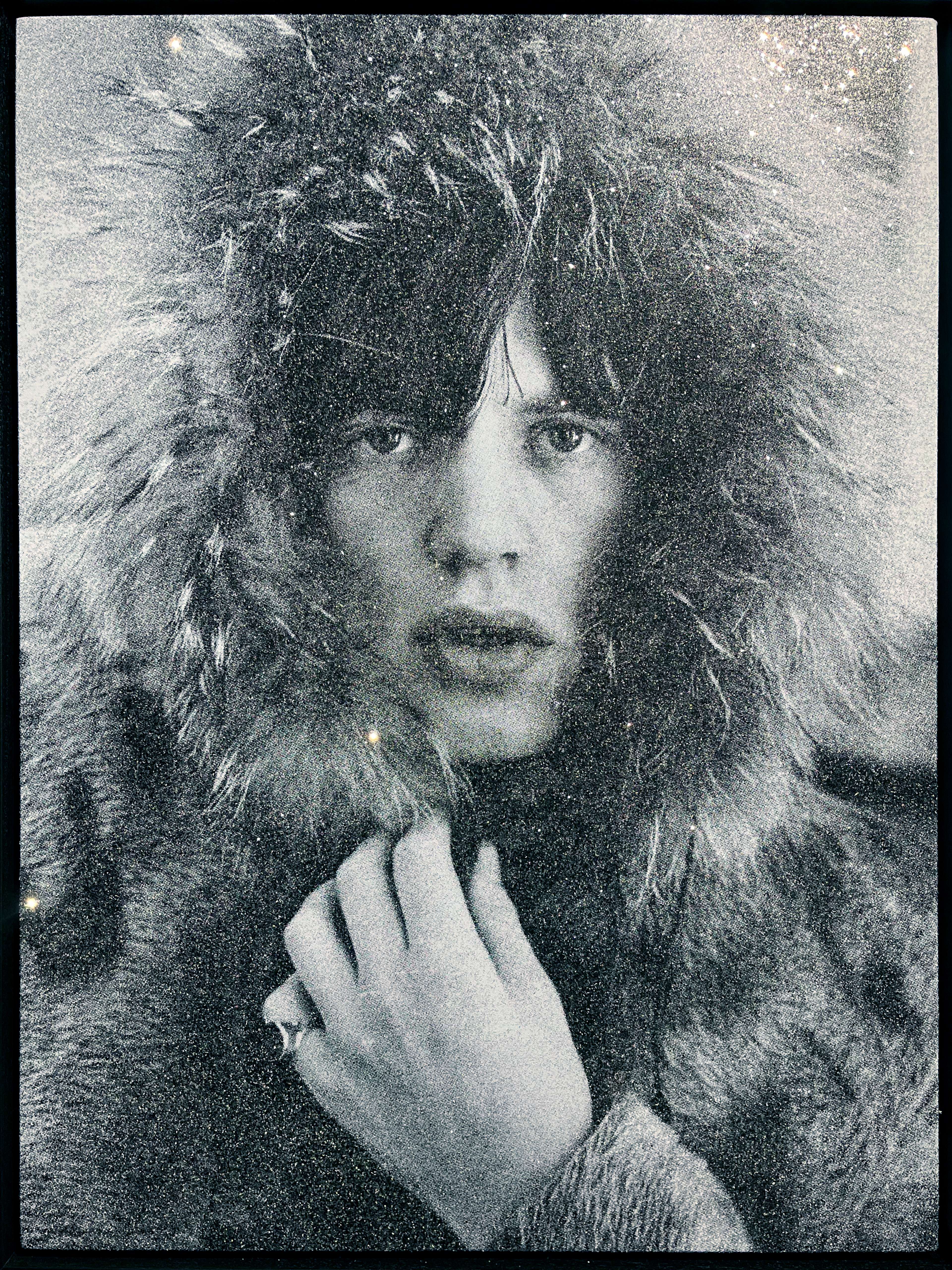 A monochrome photograph of Mick Jagger in a fur hood completely covered in diamond dust.