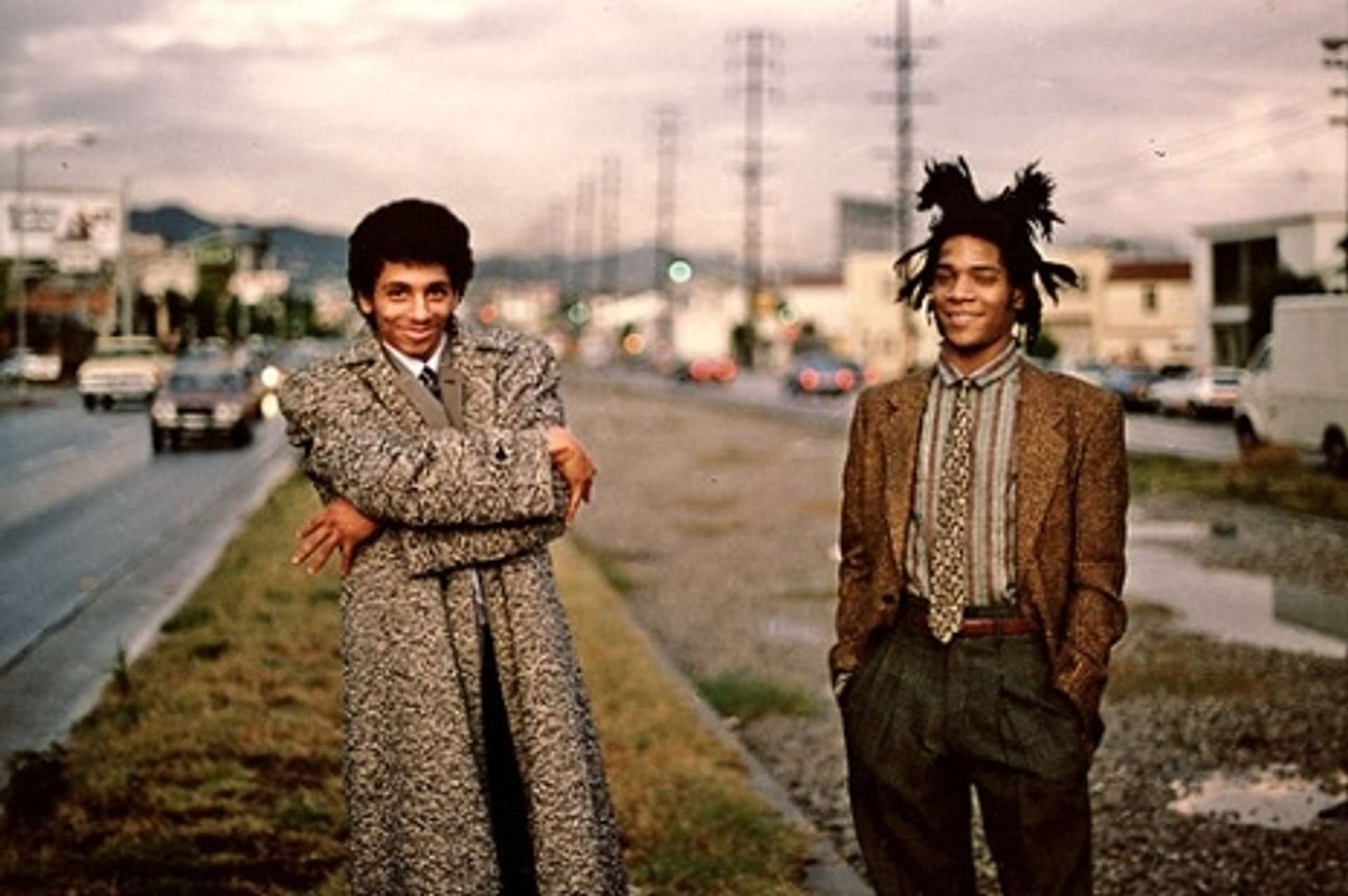 A photograph of artists Rammellzee and Jean-Michel Basquiat standing outside.
