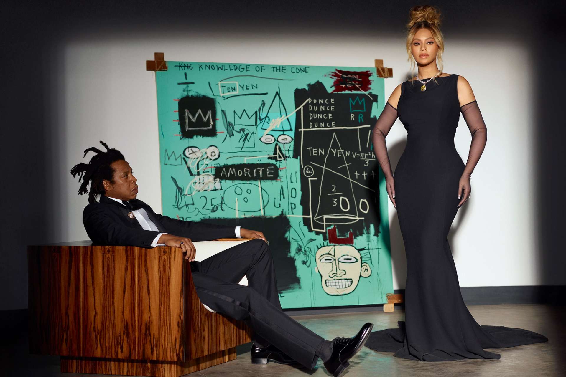 JAY-Z and Beyoncé in black tie attire posing in front of a turquoise Basquiat painting.