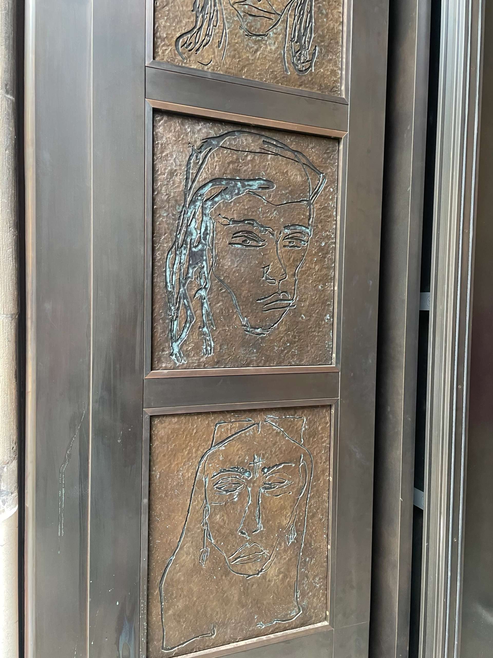 A photograph of The Doors (2023), an installation work by artist Tracey Emin. A close-up photograph of two portraits of women on the bronze doors of the National Portrait Gallery in London.