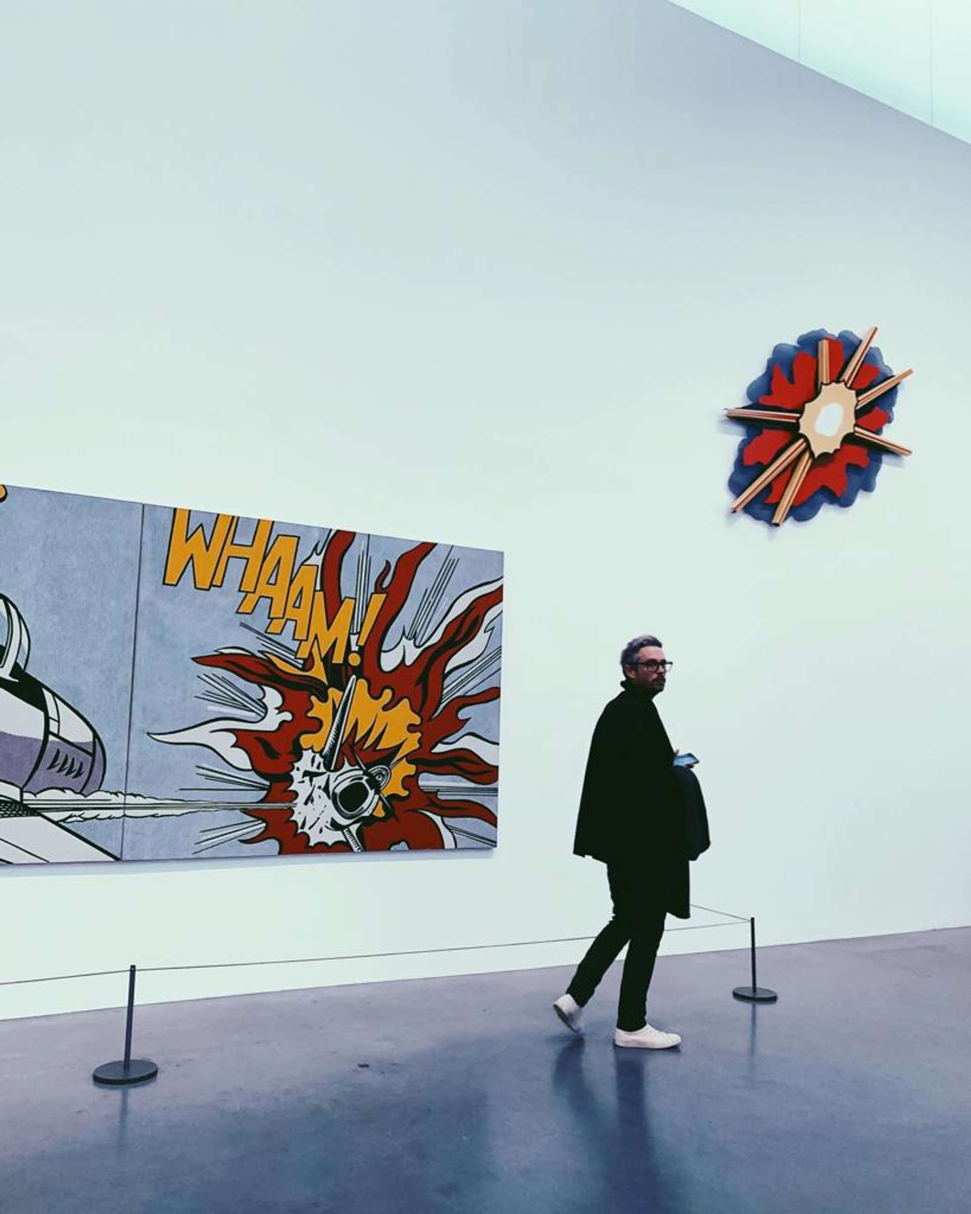 Millennial man walking in an art gallery in front of Roy Lichtenstein's Whaam!