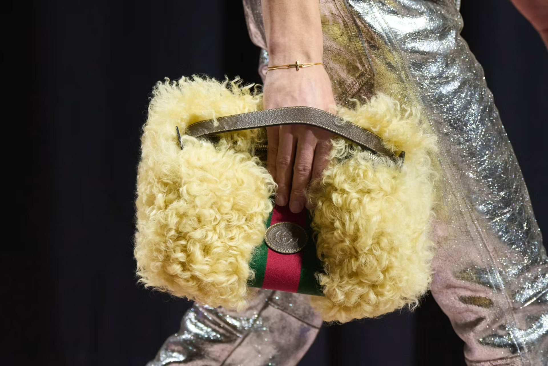Close up model walking a runway holding a Gucci fur handbag