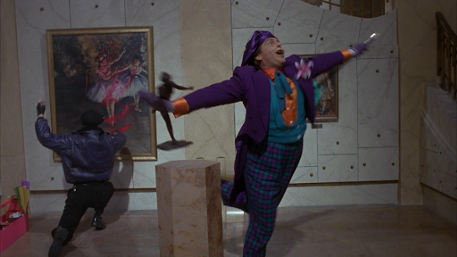 Photograph of Batman film set. Man spreading out his arms with his leg up in the air in an art gallery. 