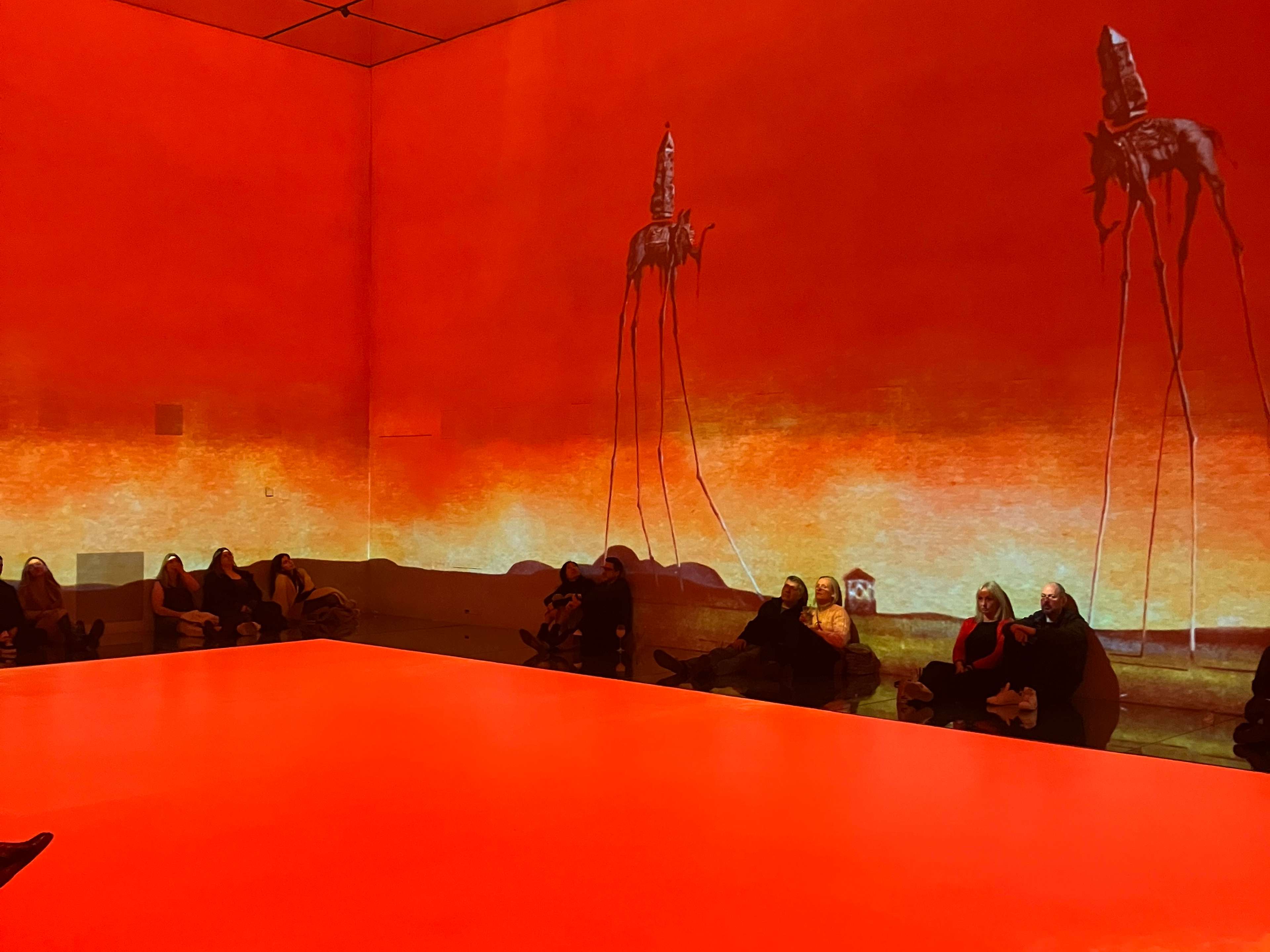 A large mirrored room in which orange landscape is projected onto every surface