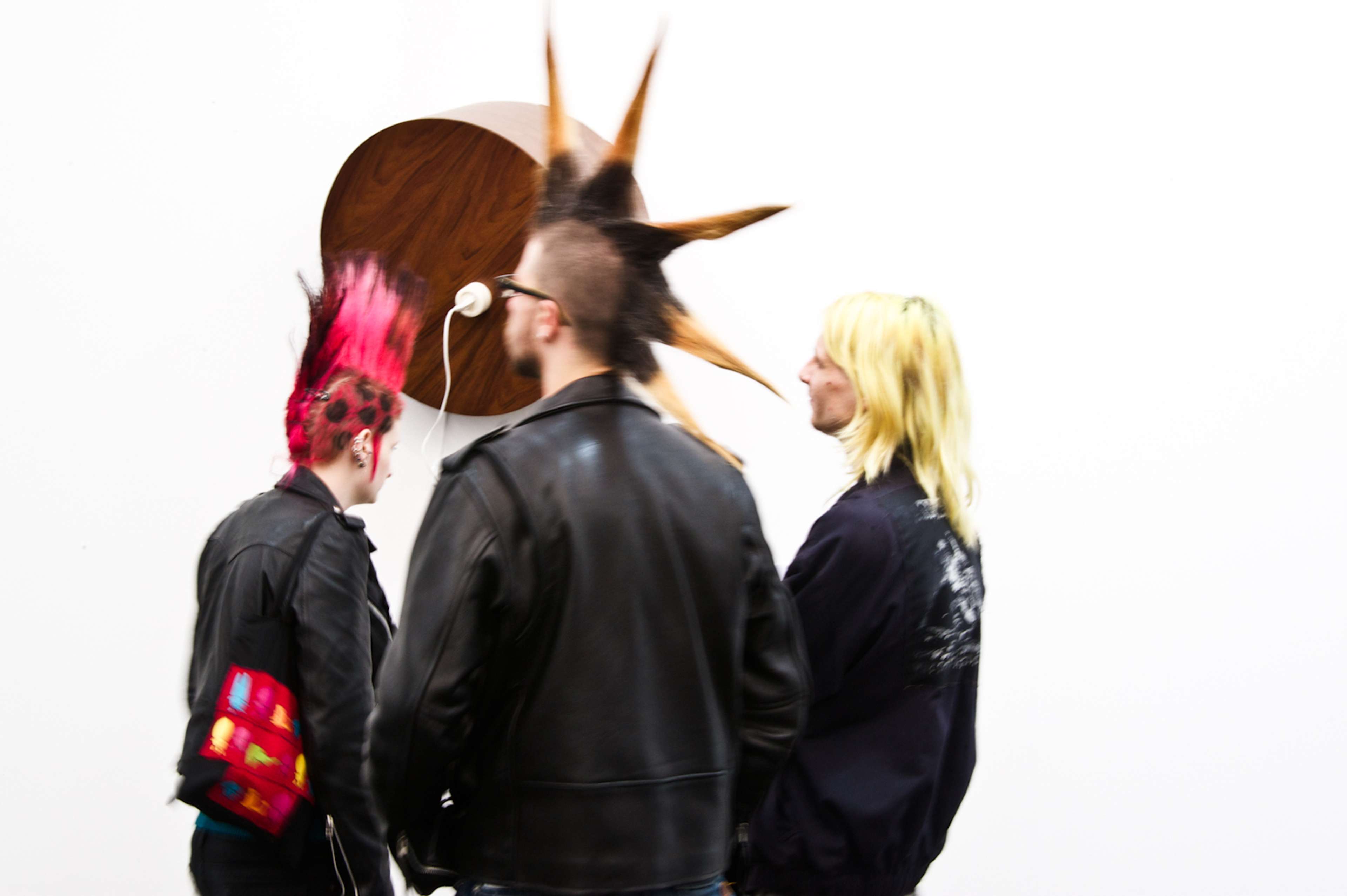 Three individuals viewing an abstract piece of art on the wall 