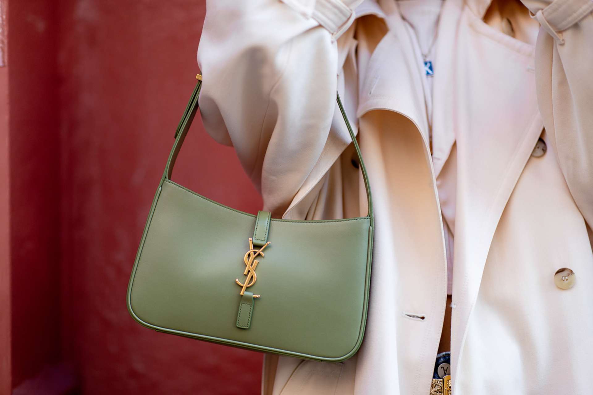An image of a model, holding a green Yves Saint Laurent Le 5 à 7 bag.