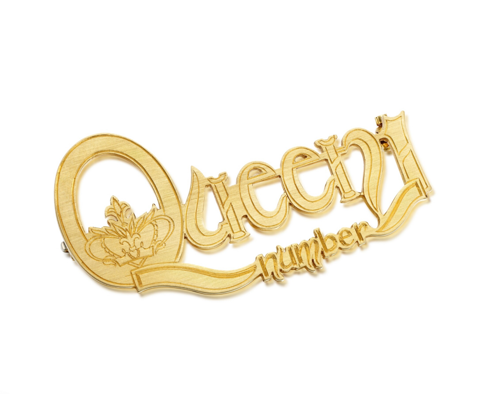 An image of a gold Cartier brooch that reads Queen number 1