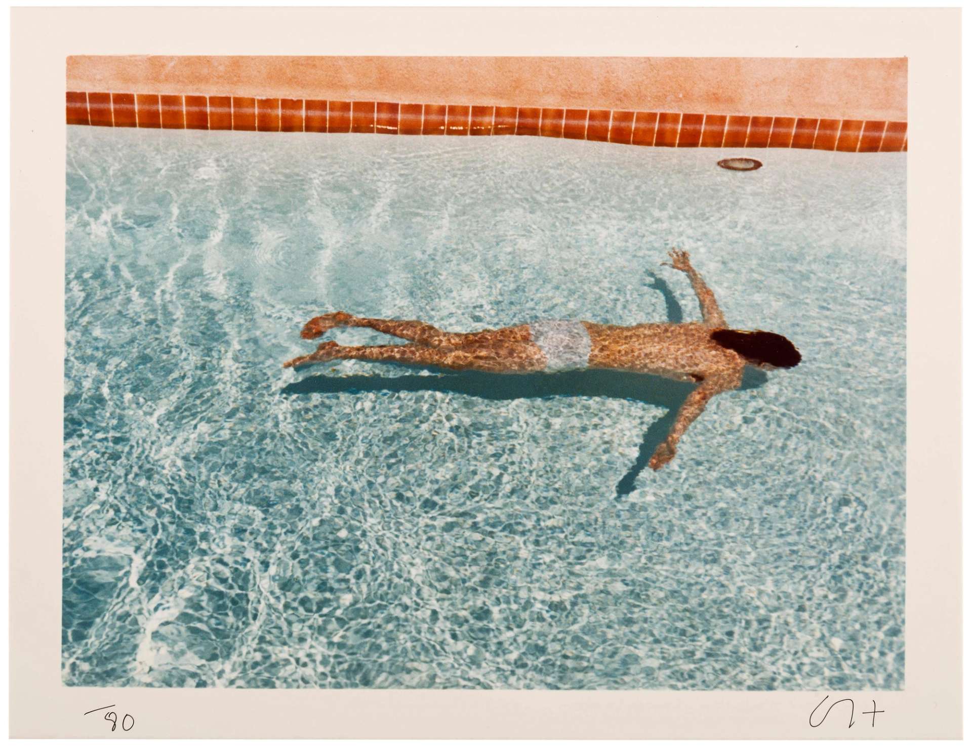 This photograph by British artist features a nude man swimming in a pool, face-down.