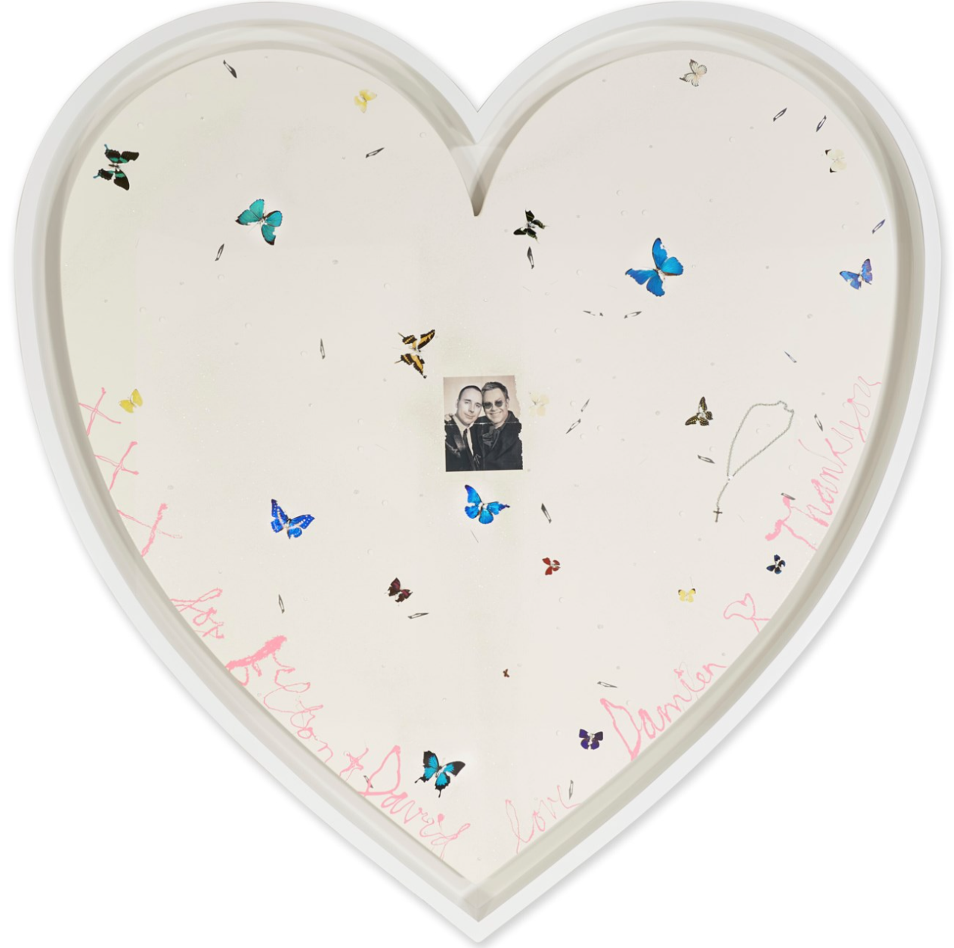 A heart-shaped canvas is scattered with butterflies surrounding a portrait of Elton John and his partner David Furness. Damien Hirst has signed it in pink.