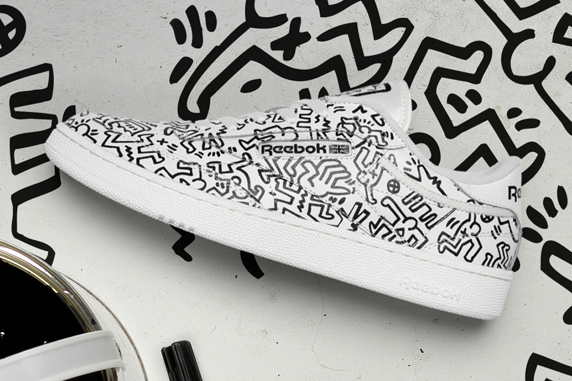 An image of a white sneaker by Reebok, fully decorated with Keith Haring's dancing figures.