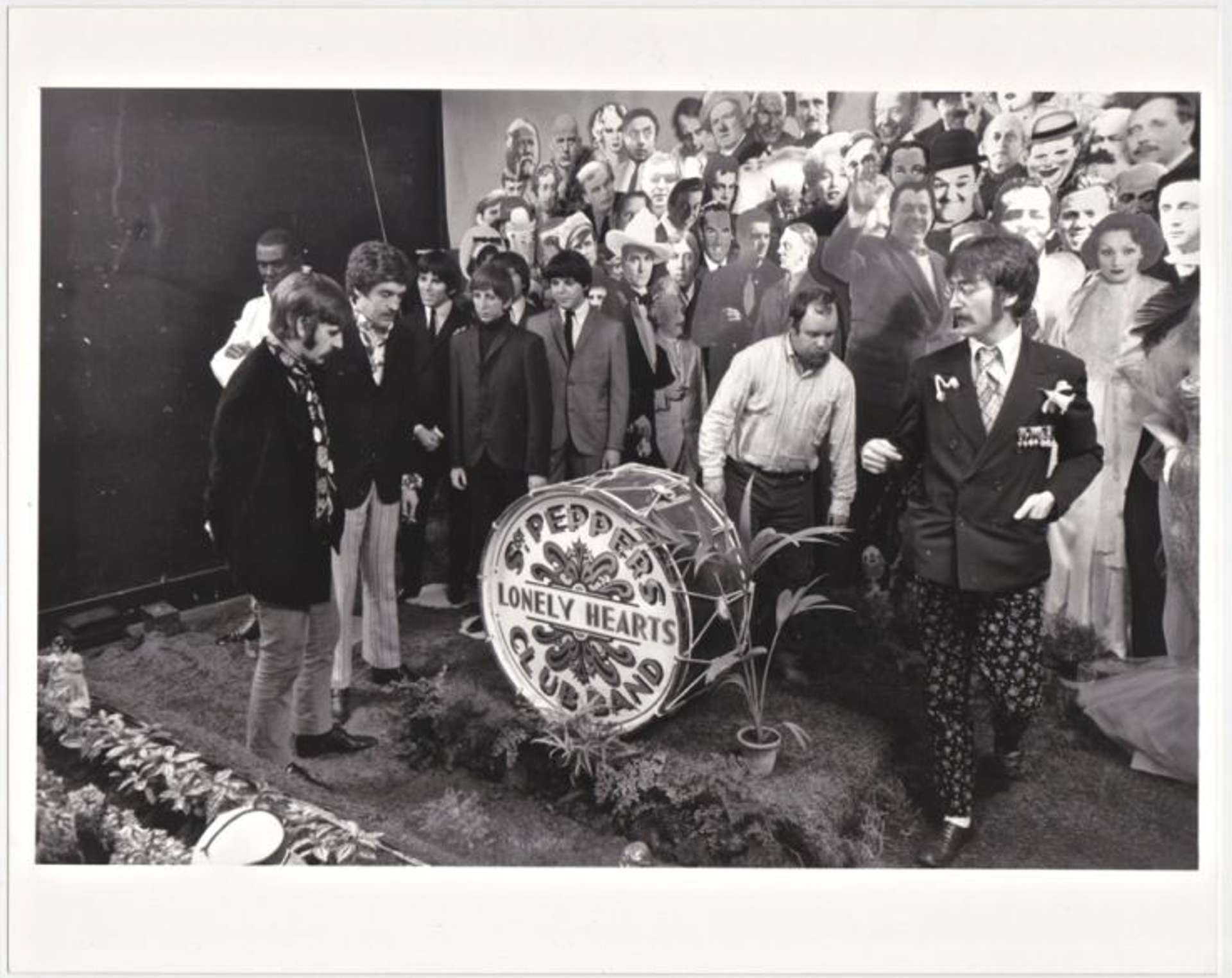 A black and white photograph of the band The Beatles and artist Peter Blake at the cover shoot for their album Sgt. Pepper’s Lonely Hearts Club Band.