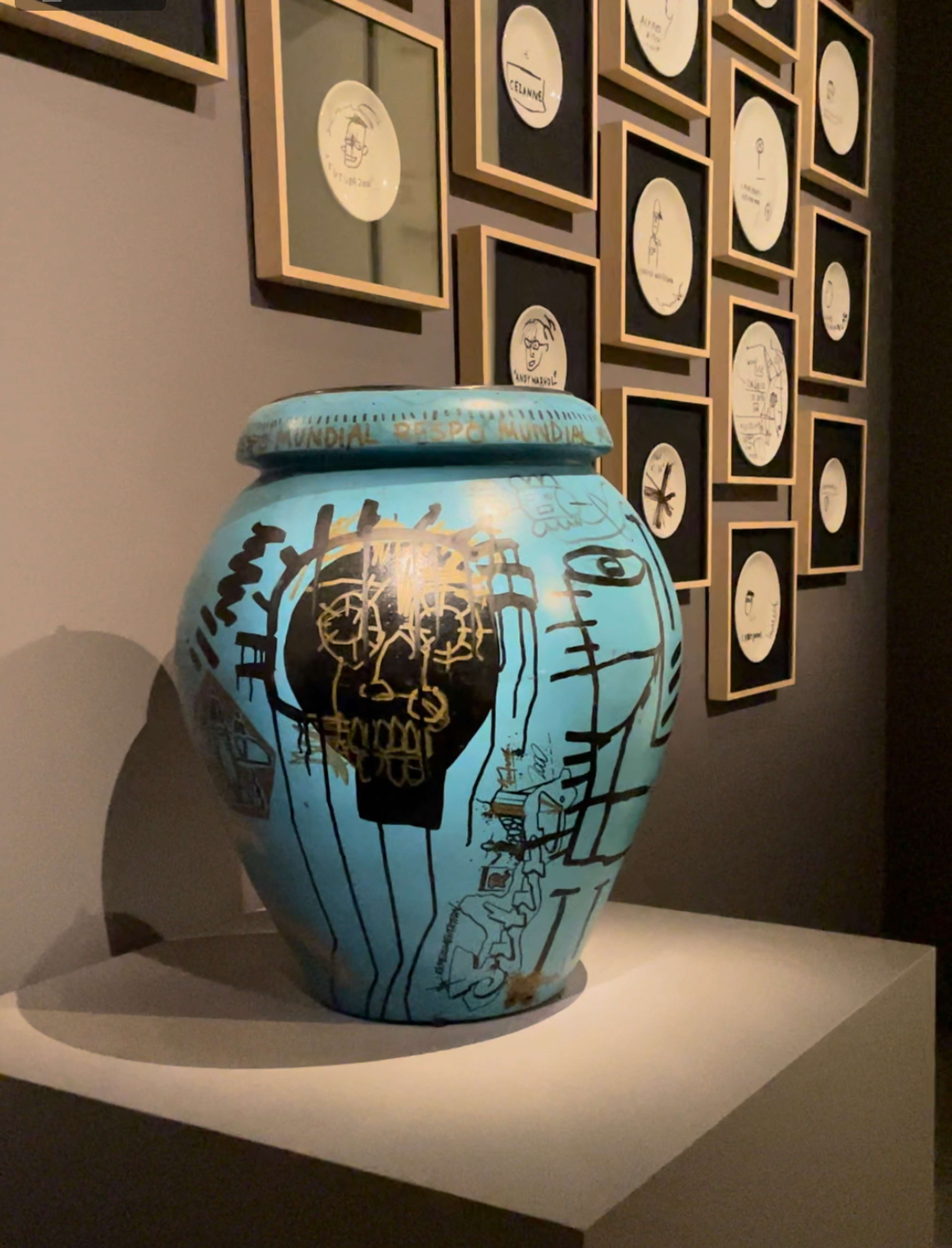 A blue vase and a wall of framed plates 