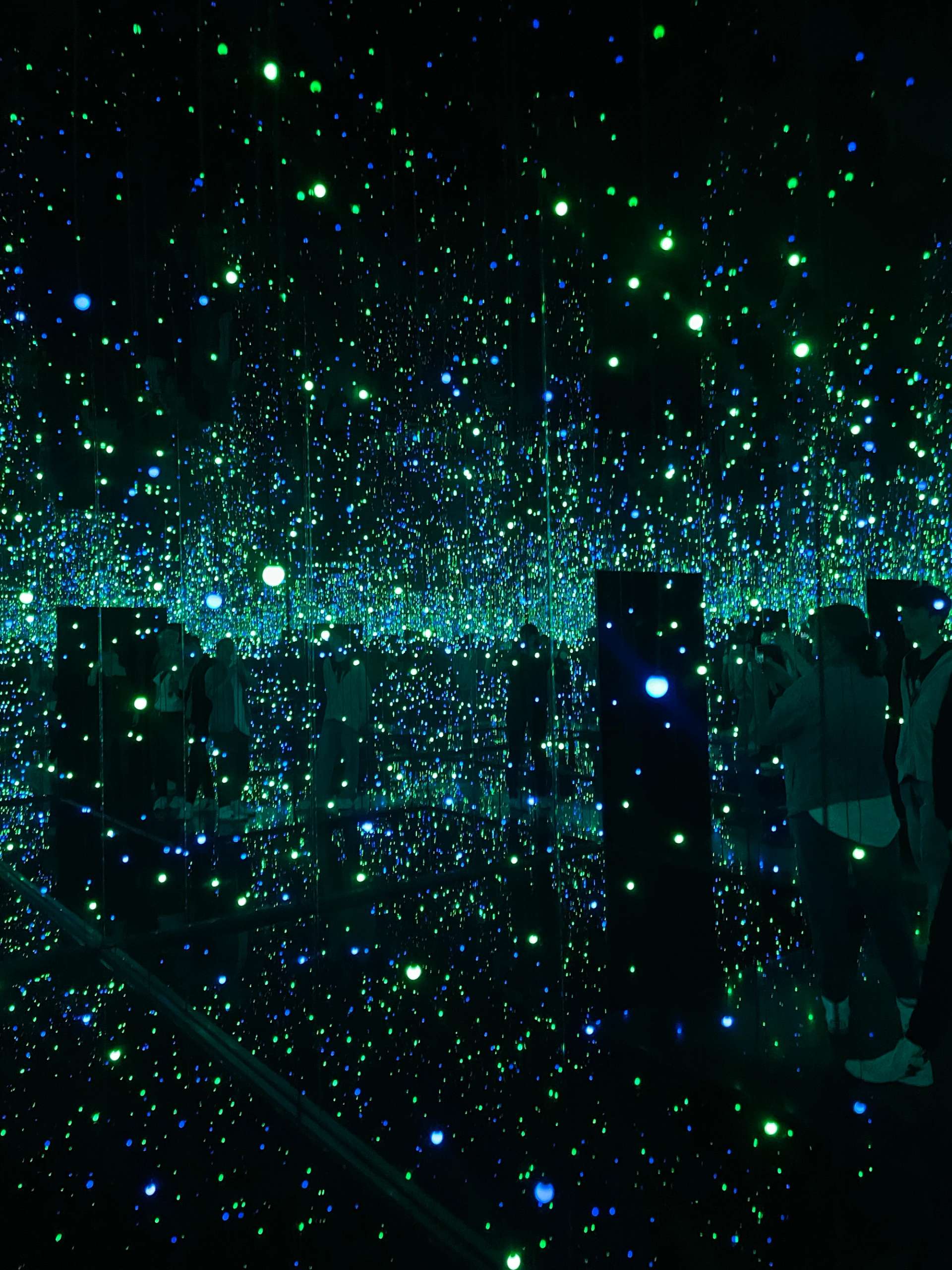 This photograph shows one of Yayoi Kusama's Infinity Rooms at the Tate Modern 2023, a mirrored environment with thousands of bright coloured lights.