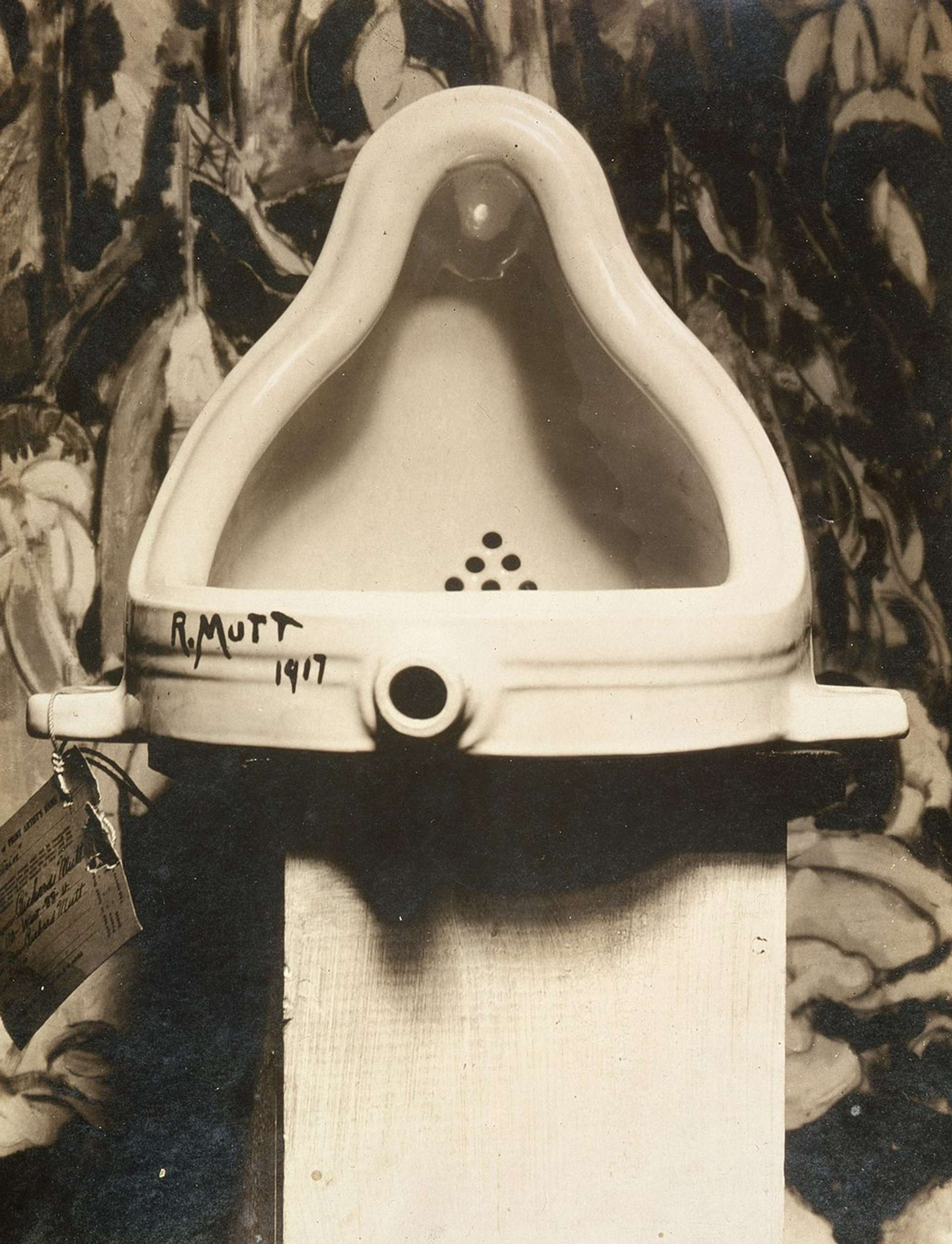 n image of the urinal that became Fountain by Marcel Duchamp. It is a white urinal, with the signature R. Mutt 1917 on the bottom left corner.