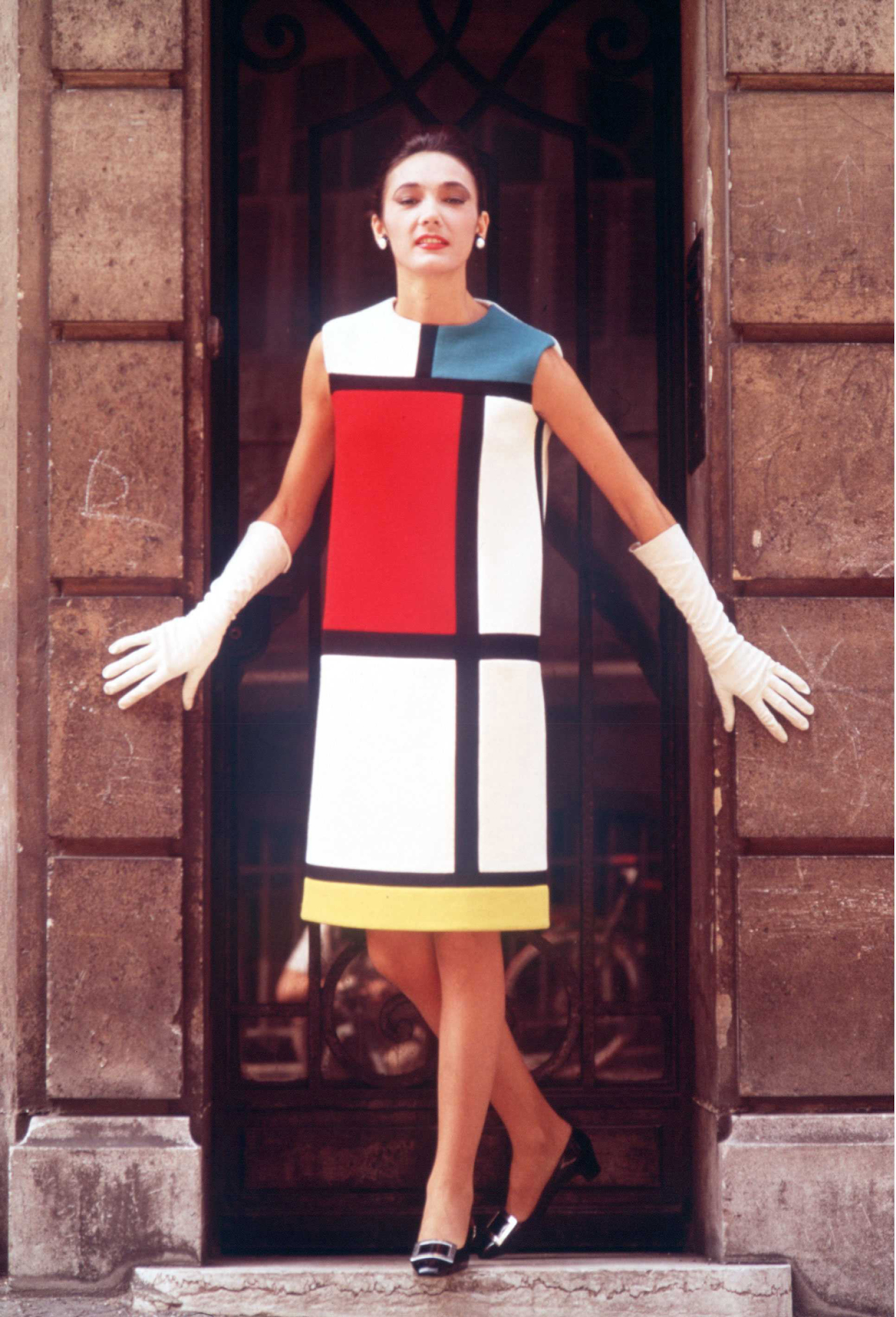 Woman stood in a doorway wearing a cocktail dress with graphic white, red, yellow and blue rectangles on defined by thick black lines