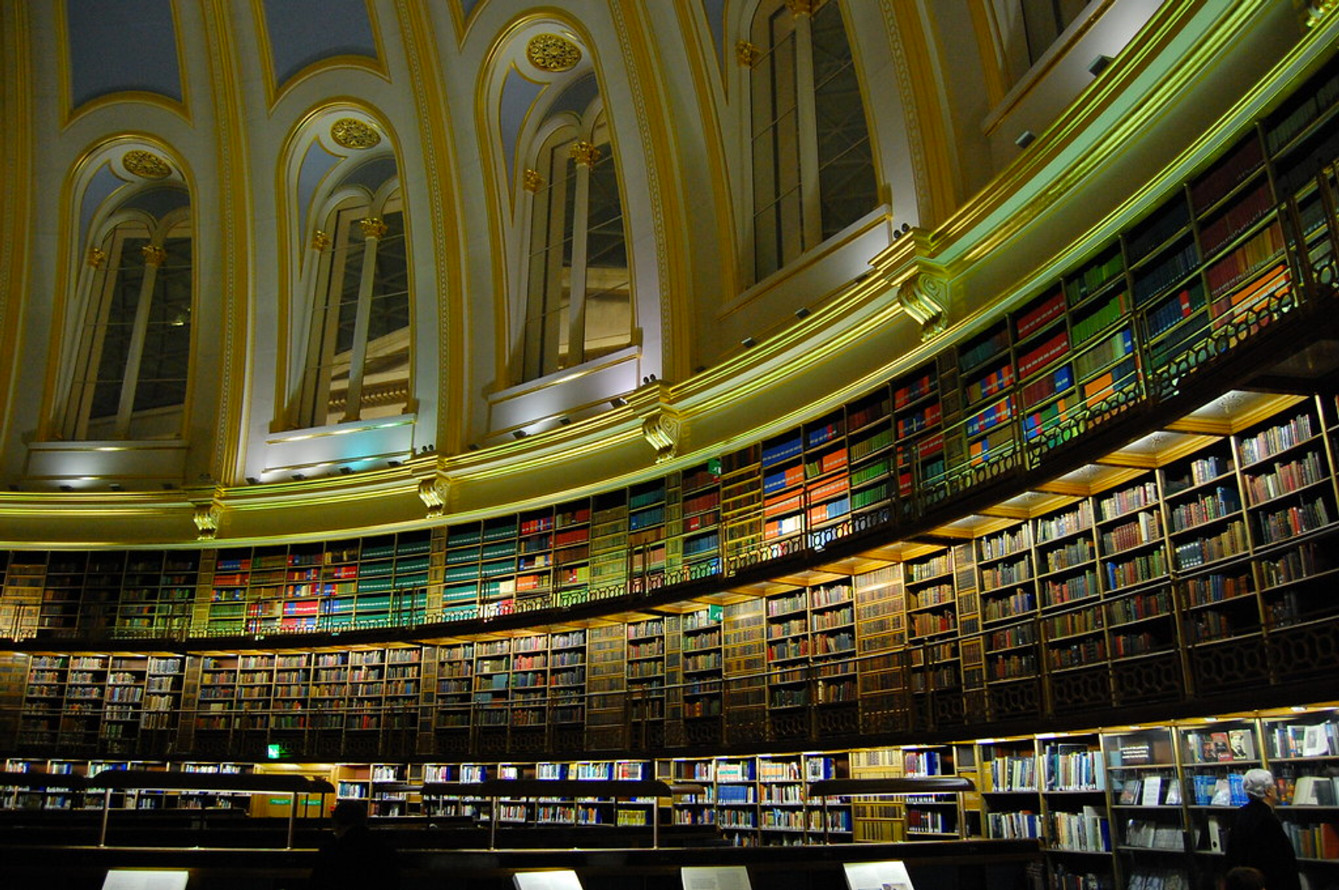 An image of the reading room at the British Library, featuring thousands of books on shelves within a domed structure.