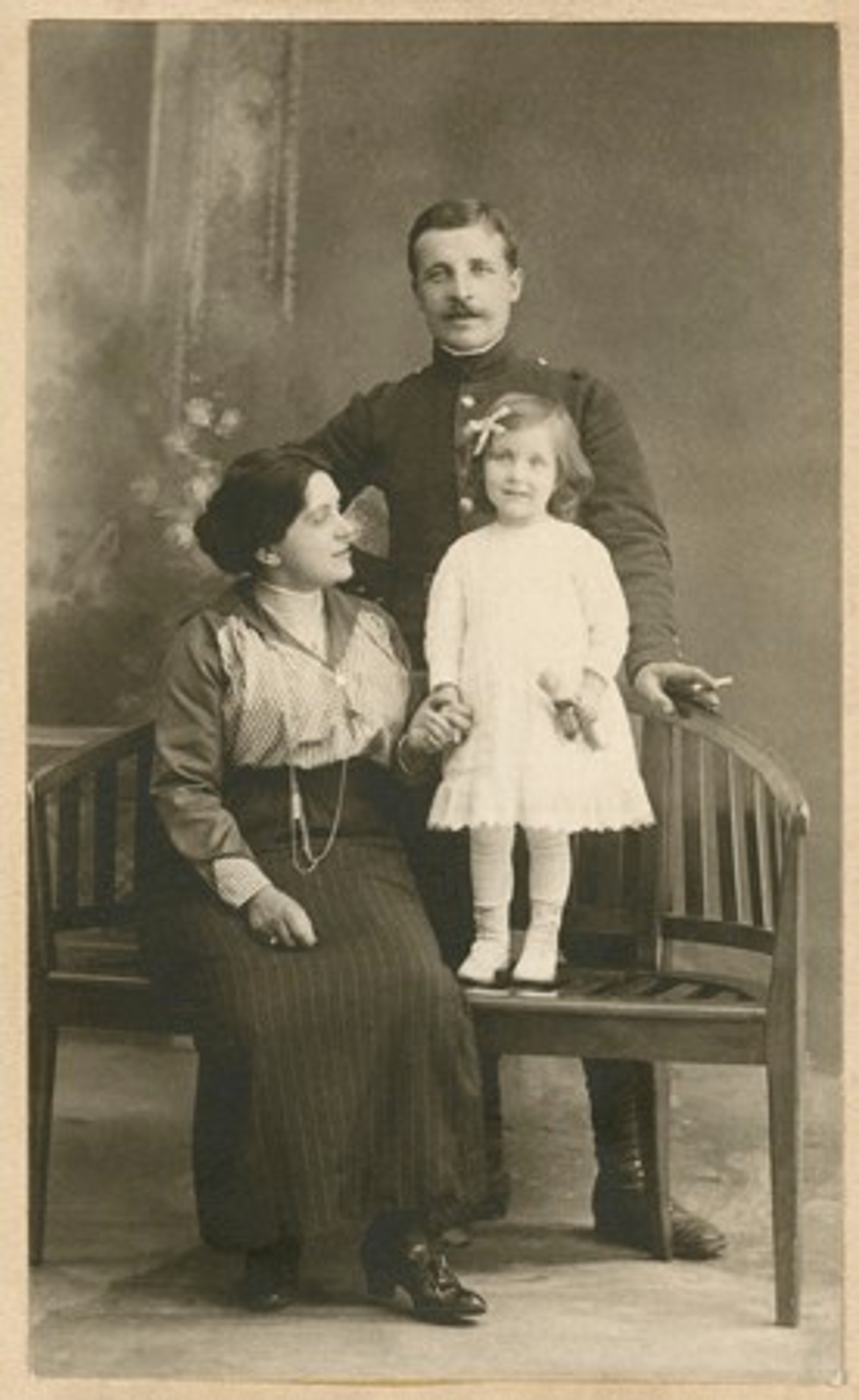 Photograph of a young Louise Bourgeois with her parents. Her father standing behind her, and her mother to the right of her, holding her hand.