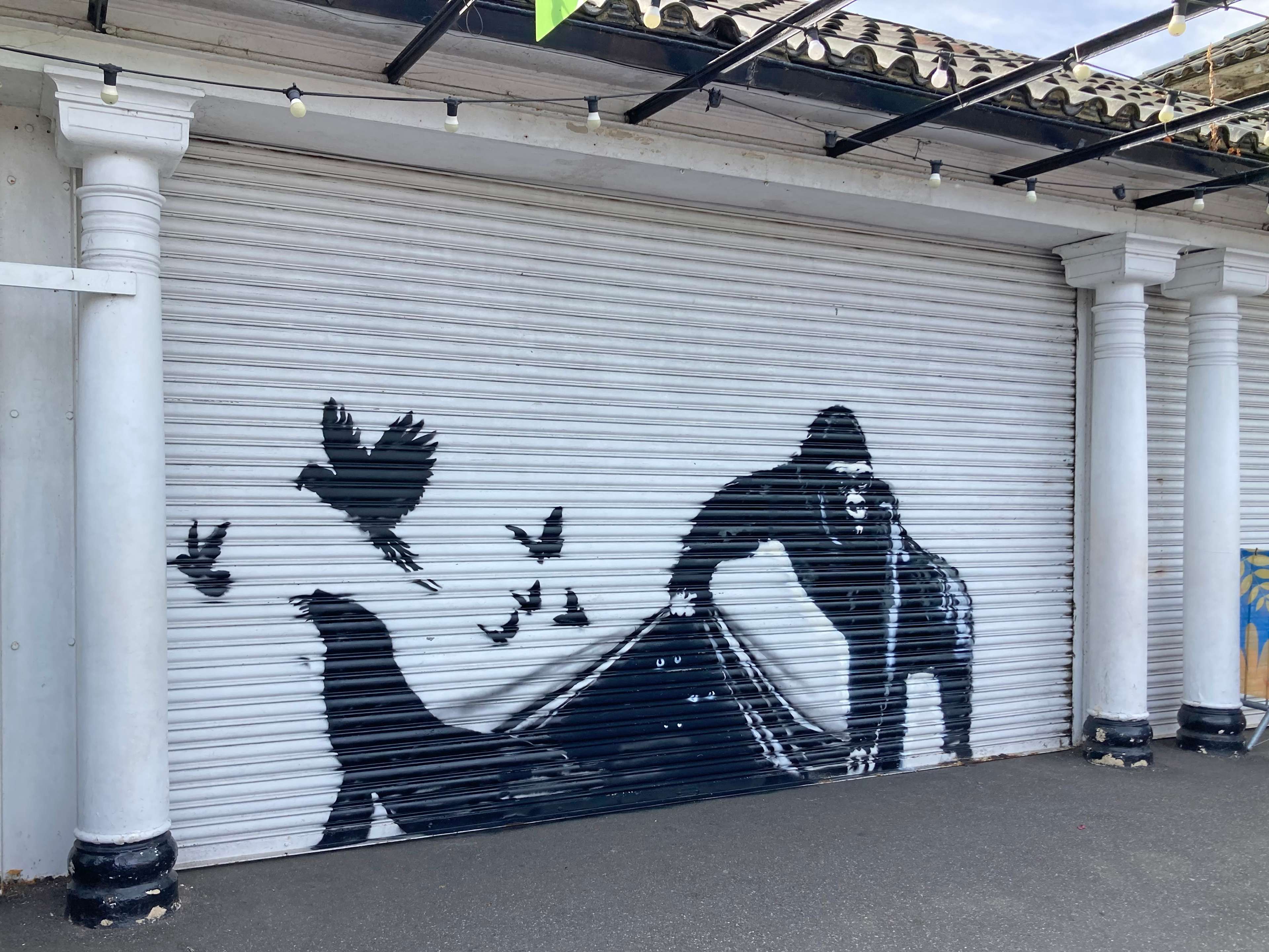 Spray painted gorilla lifting a sheet to allow other spray painted animals to escape 