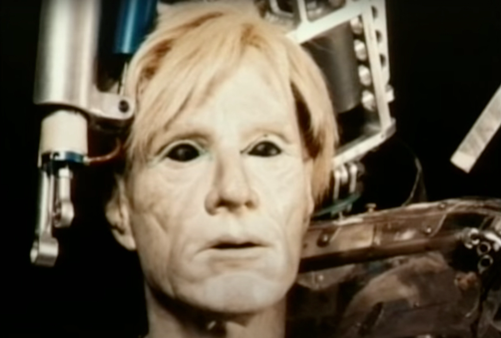 A screenshot of a video showing the face of Andy Warhol's 1981 Robot, in the likeness of the artist.