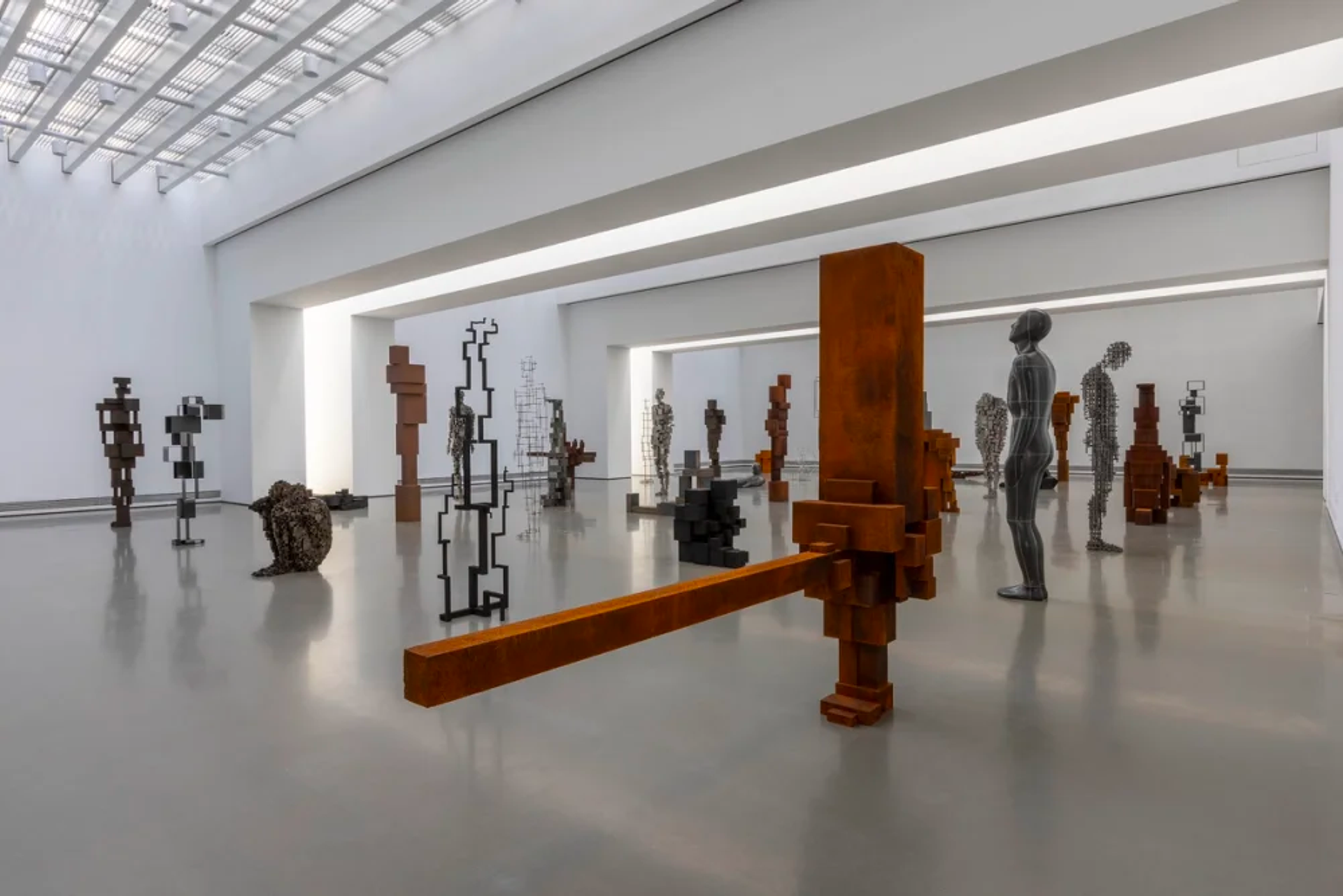 An installation view of various sculptures resembling the human form built from metal and steel.