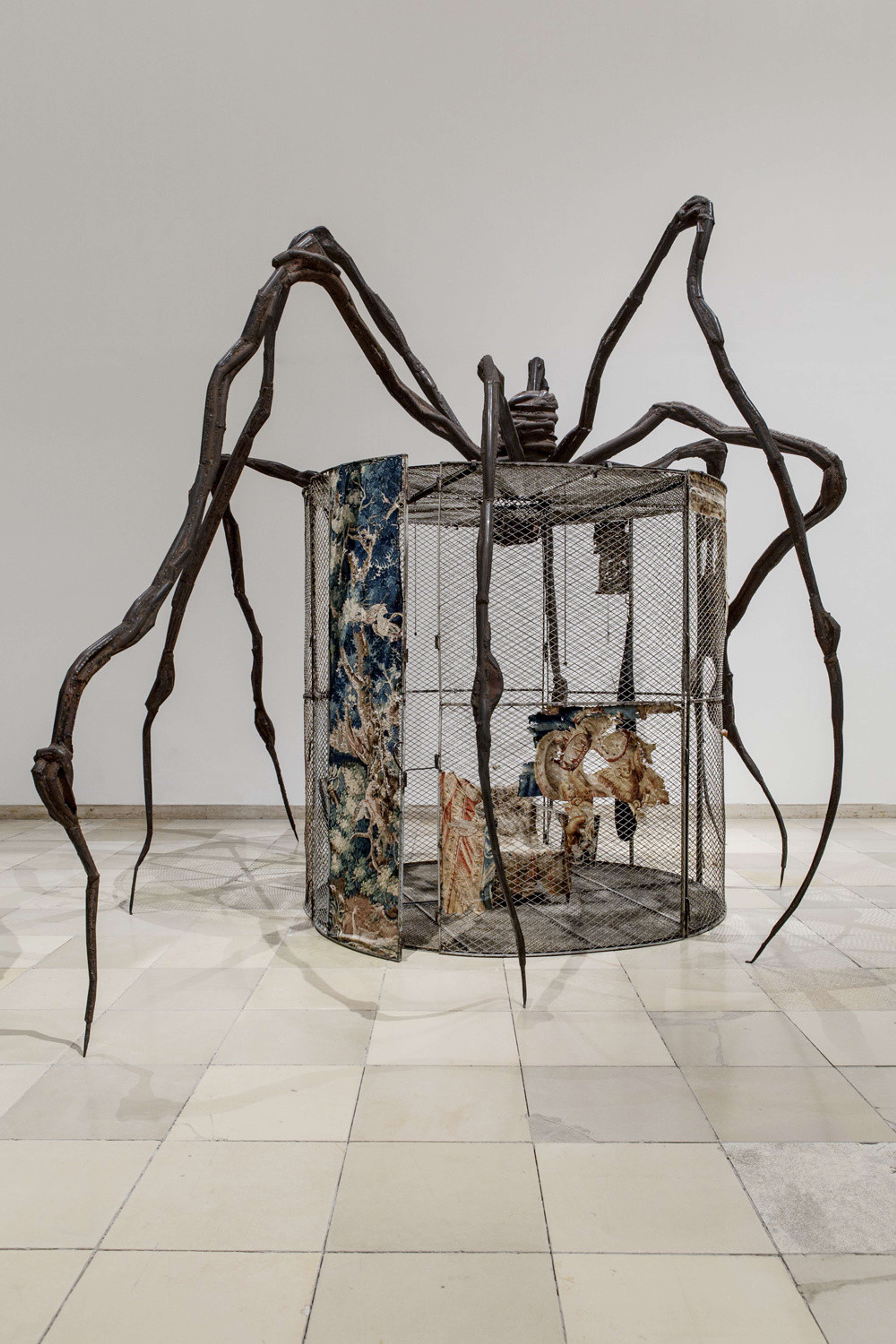 Une sculpture d'araignée de Louise Bourgeois engloutissant une installation de cage dans une galerie.