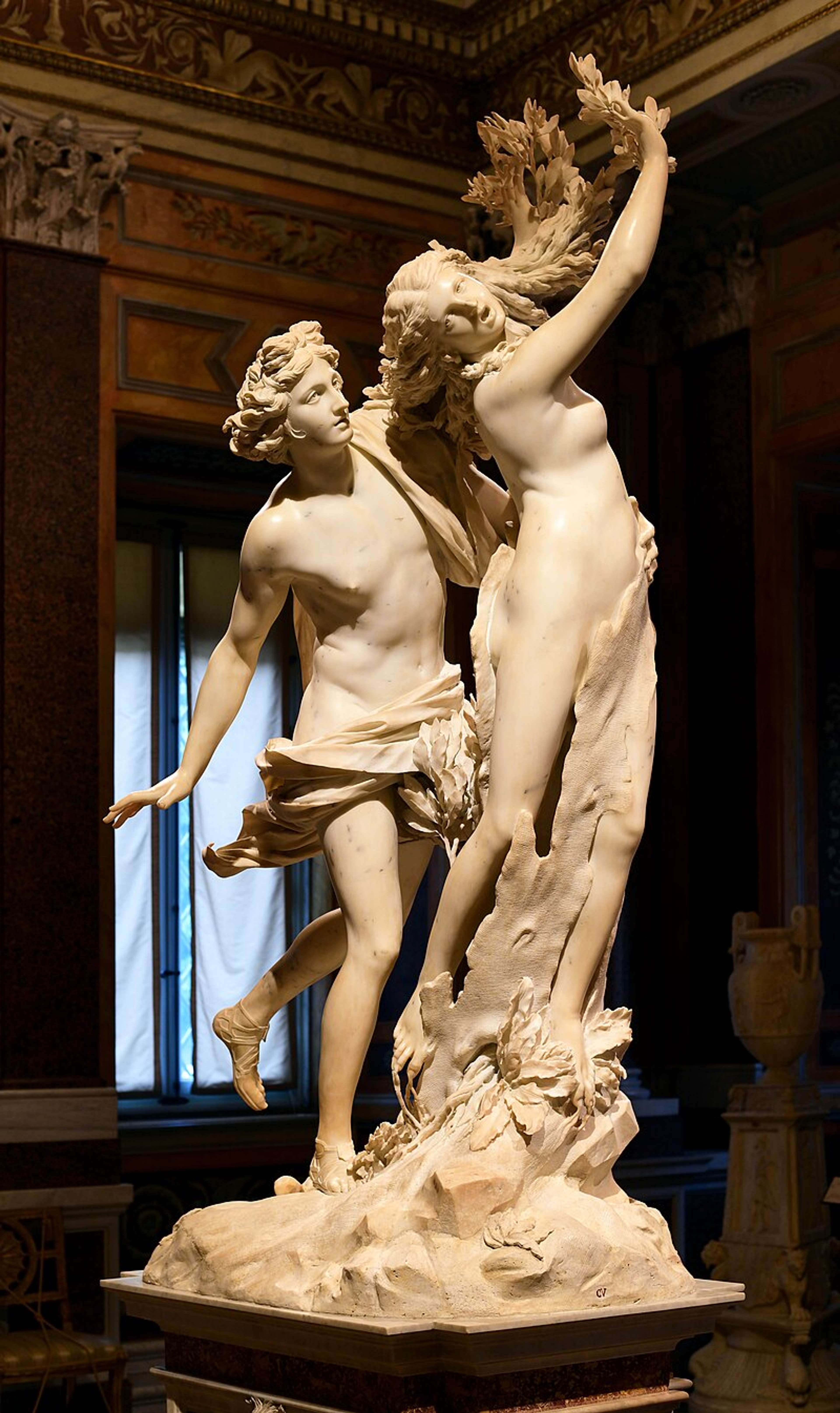 Une sculpture en marbre représente Apollon tendant la main vers Daphné alors qu'elle se tord pour s'échapper, ses doigts et ses membres se transformant en branches d'arbre et en écorce en plein mouvement.