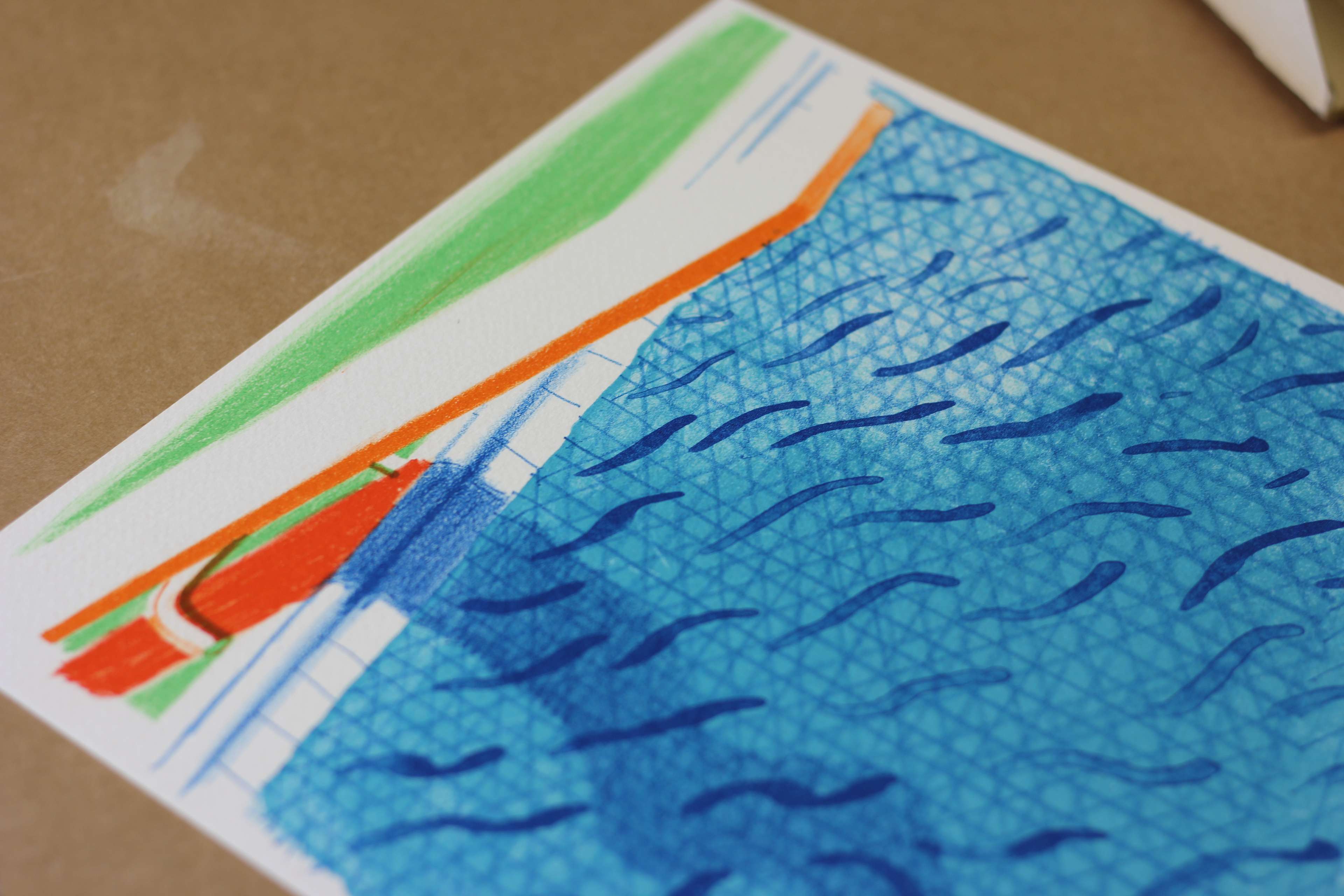 Photographie en gros plan d'une estampe représentant un plongeoir blanc et orange surplombant une piscine bleue, intitulée « Over And Over And Over » ou « Swimming Pool ».