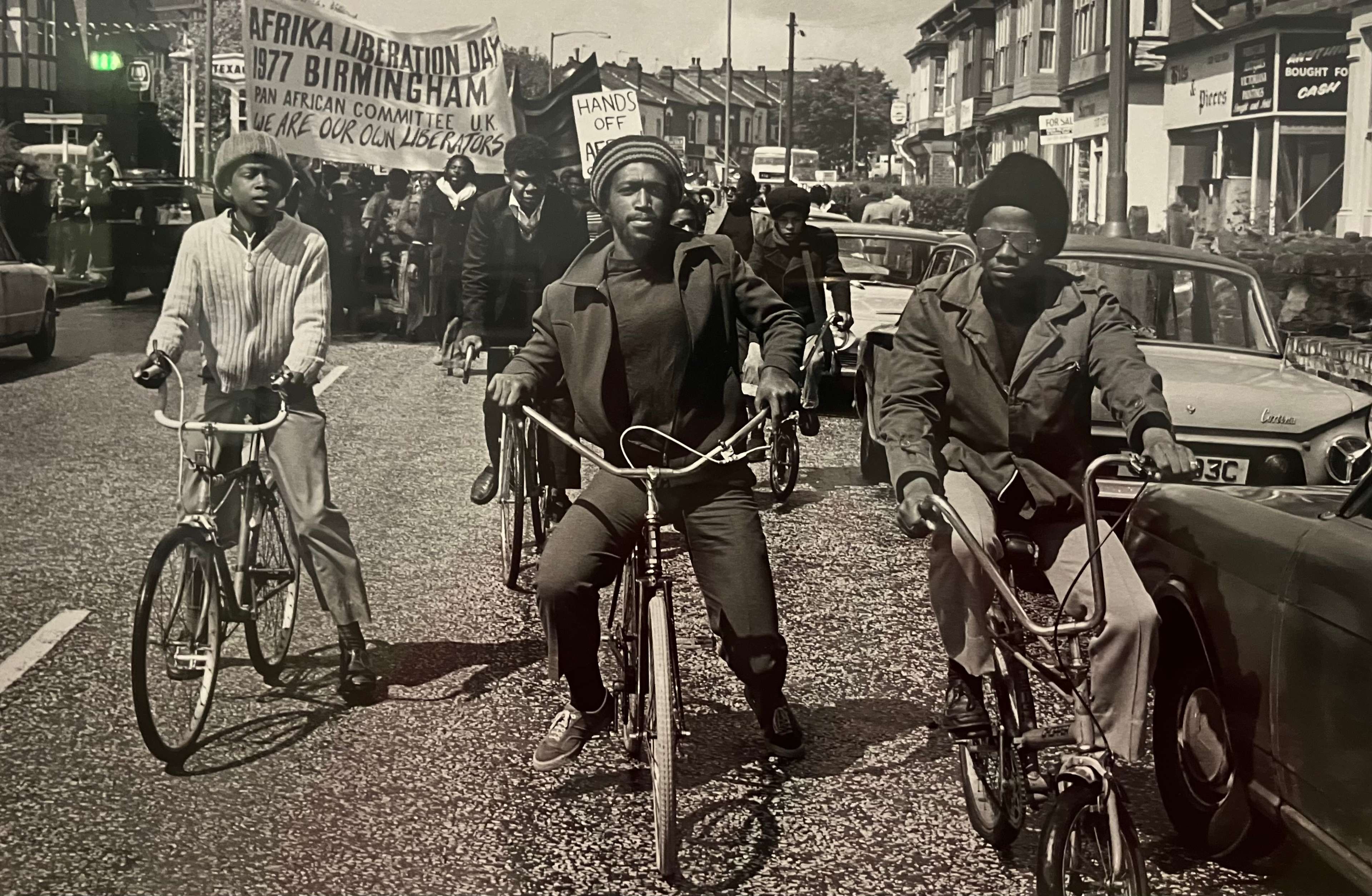 Trois hommes à vélo devant une foule de manifestants
