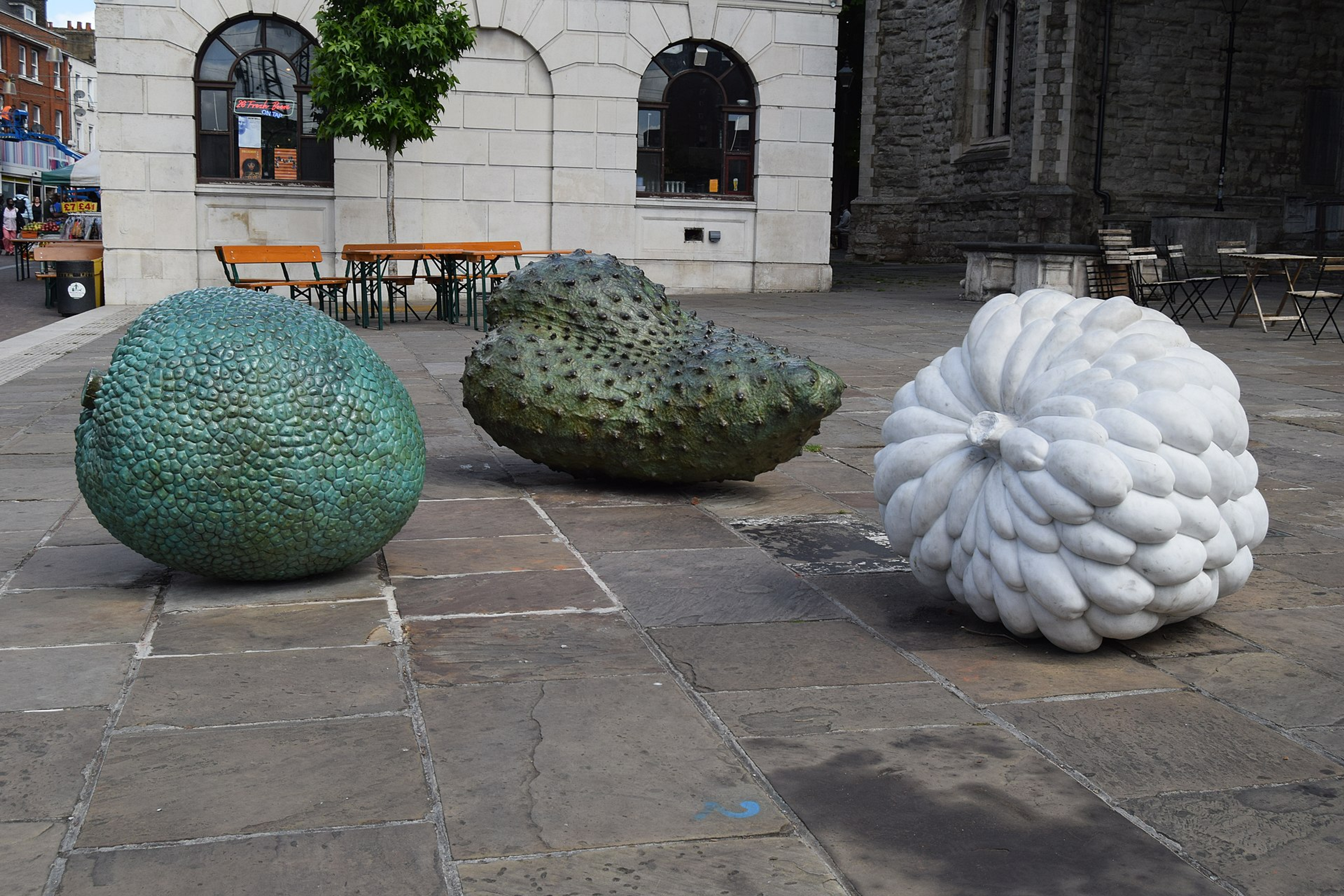 Les sculptures réalistes de grande taille représentant trois fruits des Caraïbes, posées sur le sol au milieu d'une place à Londres.